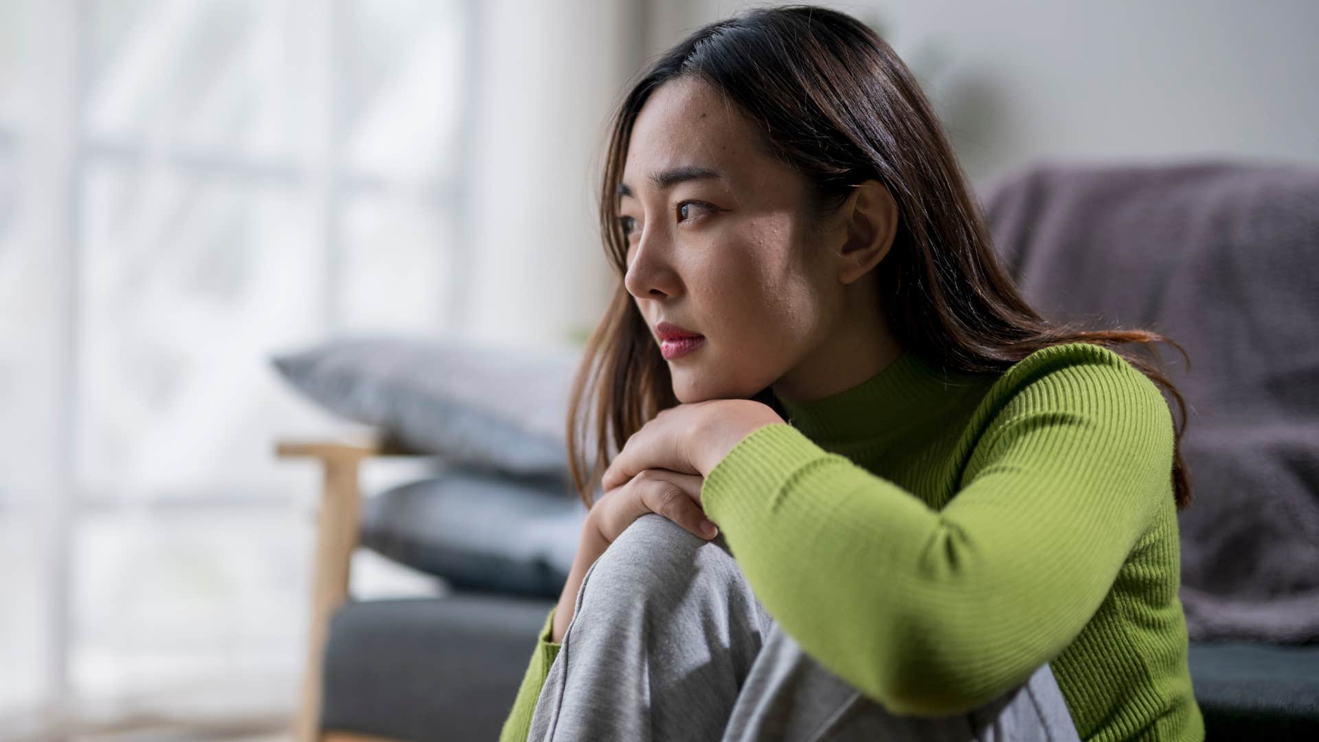 Adult woman looking upset sitting on the floor. 