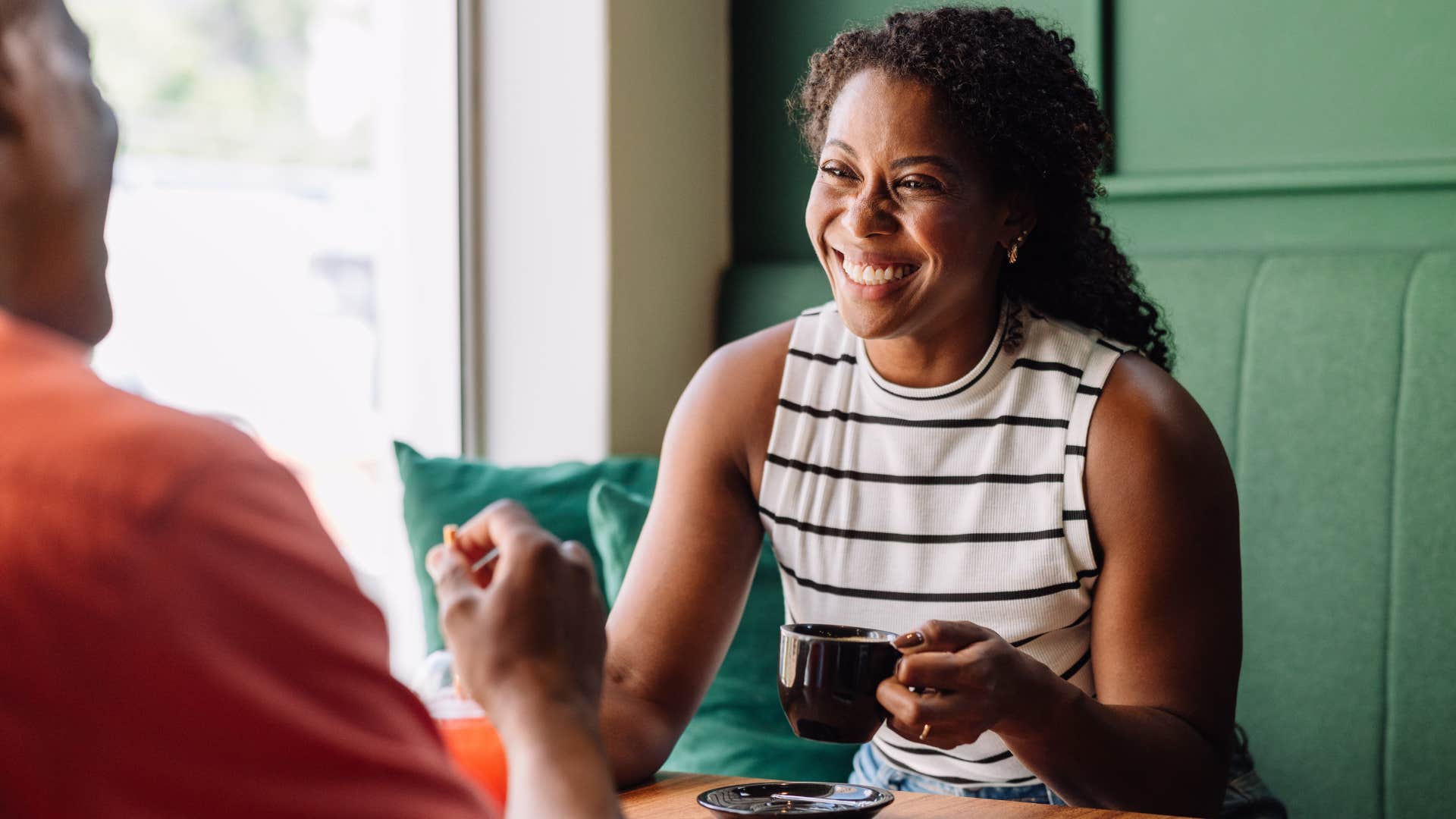 Woman smiling at a man with a cup of coffee in her hands