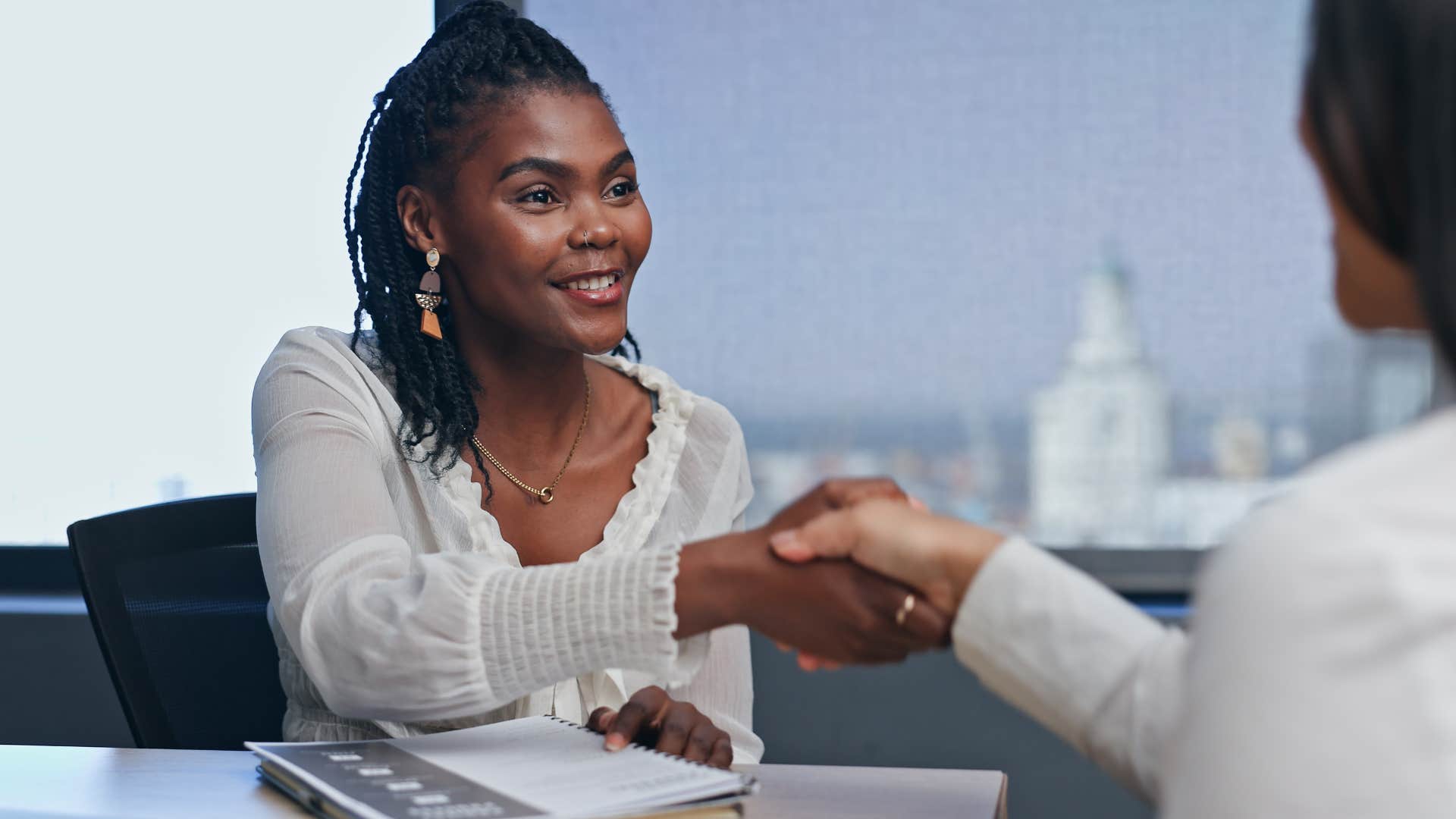 Woman smiling and shaking a person's hand