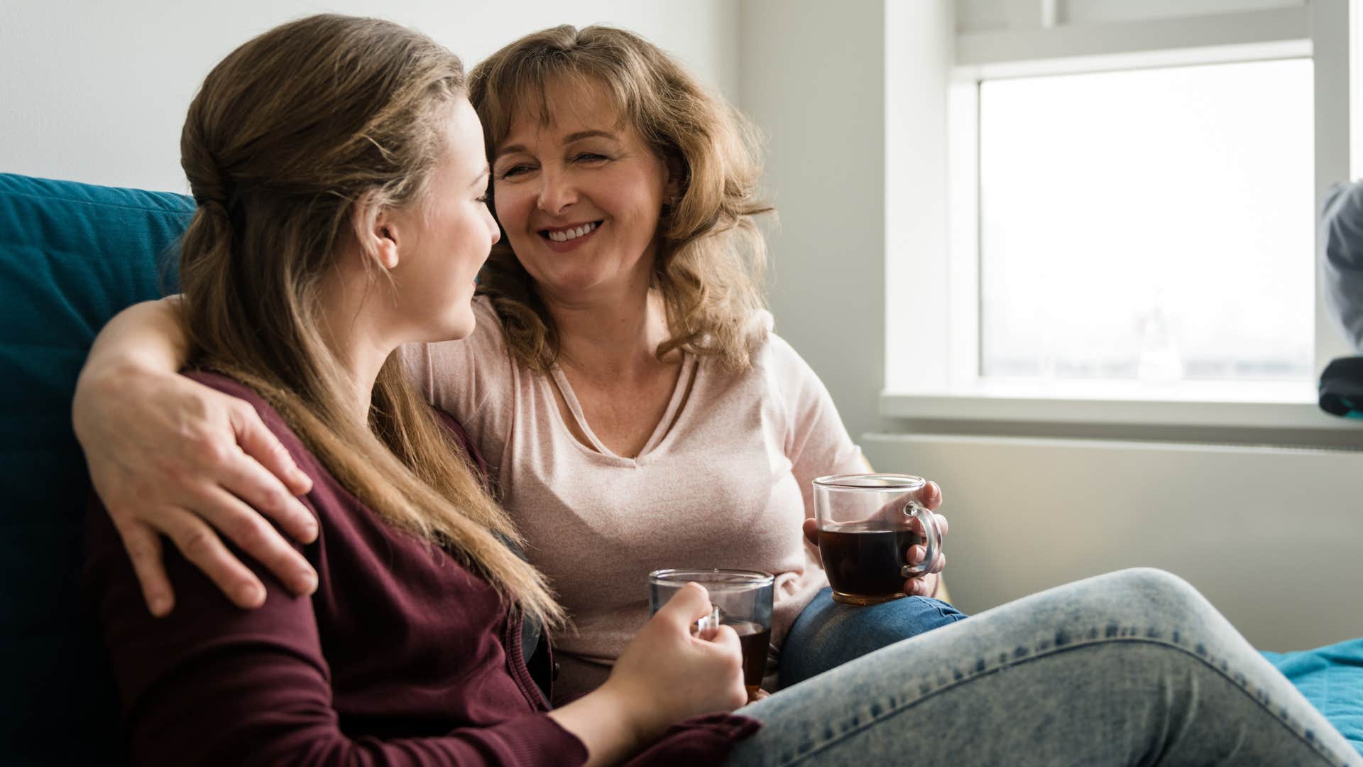 Woman hugging her mother and drinking coffee