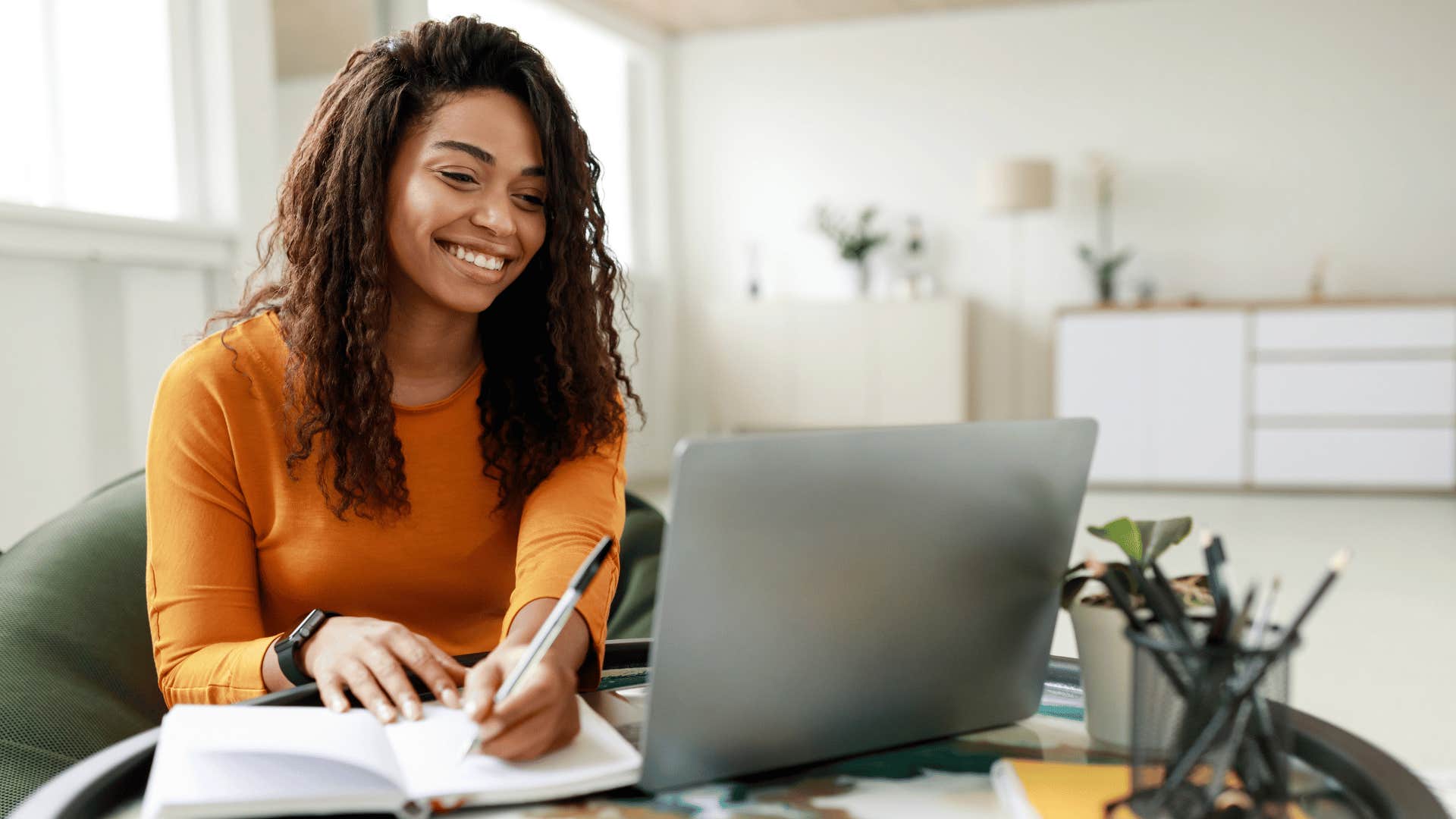 woman working on laptop and taking notes