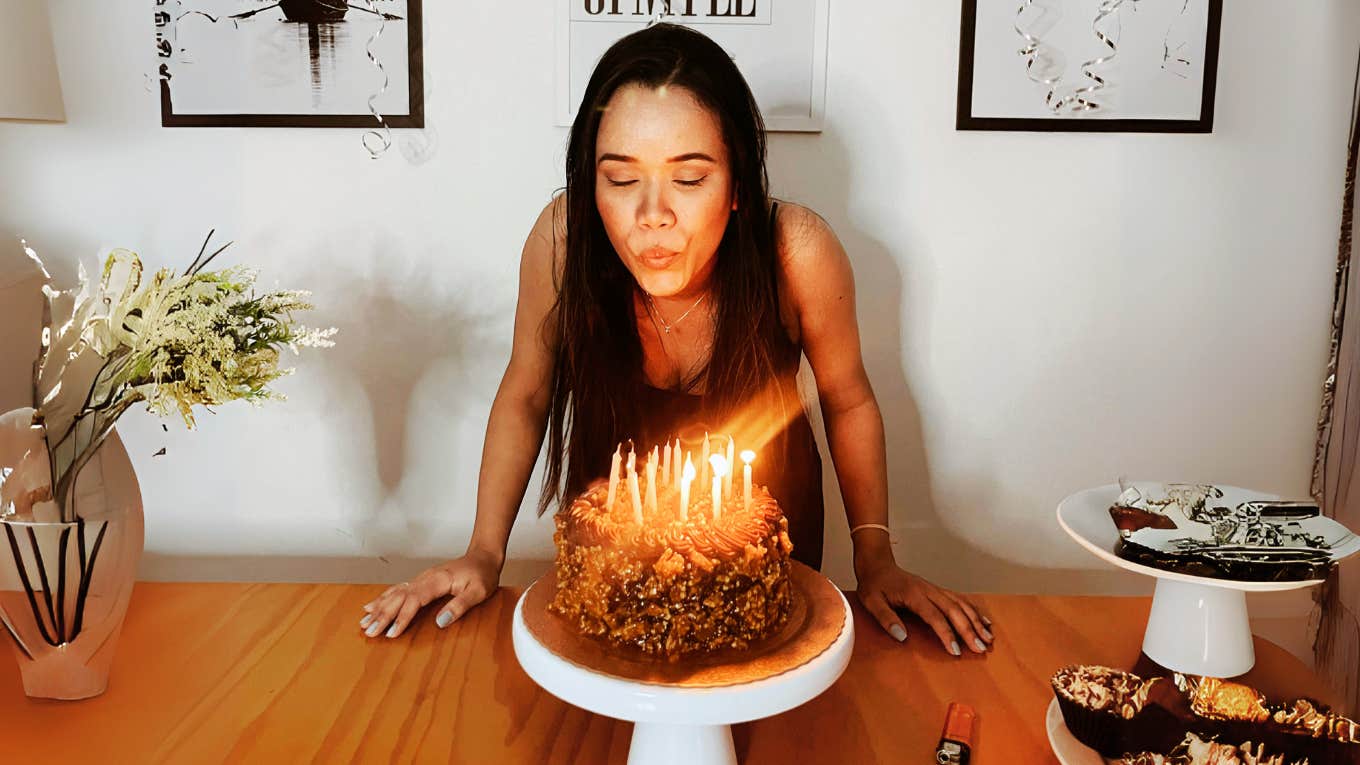 Woman blowing out birthday candle, celebrating childhood pagan tradition.