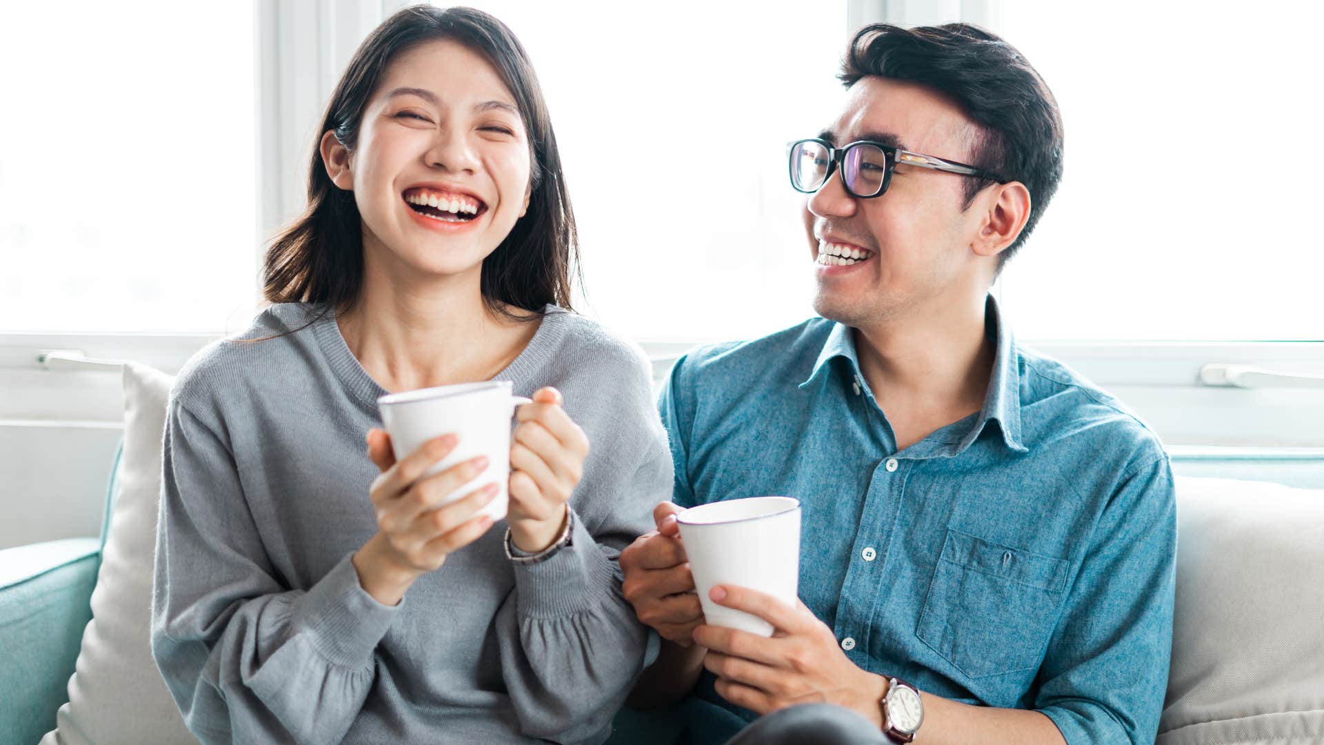 Couple smiling and drinking coffee together.