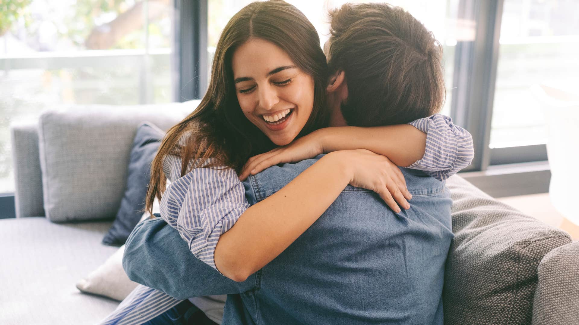 Woman hugging her boyfriend on the couch.