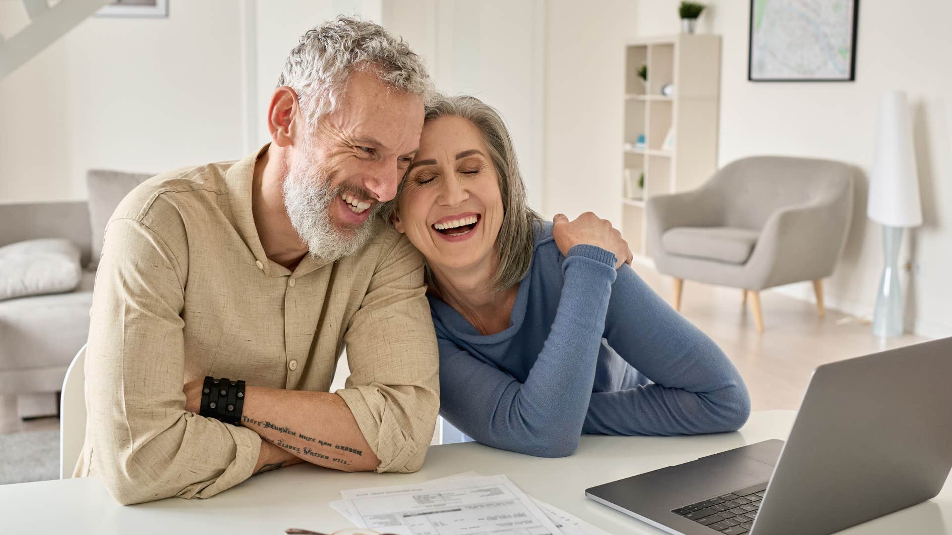 Older couple smiling and working on bills together.