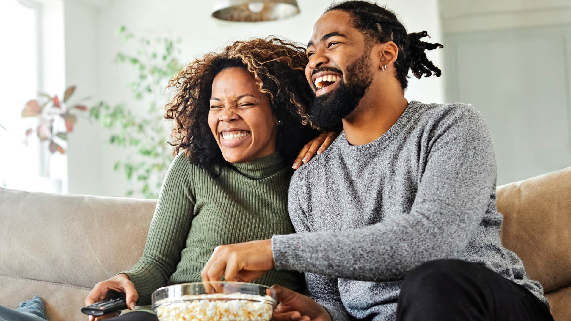 Couple smiling and eating popcorn together.