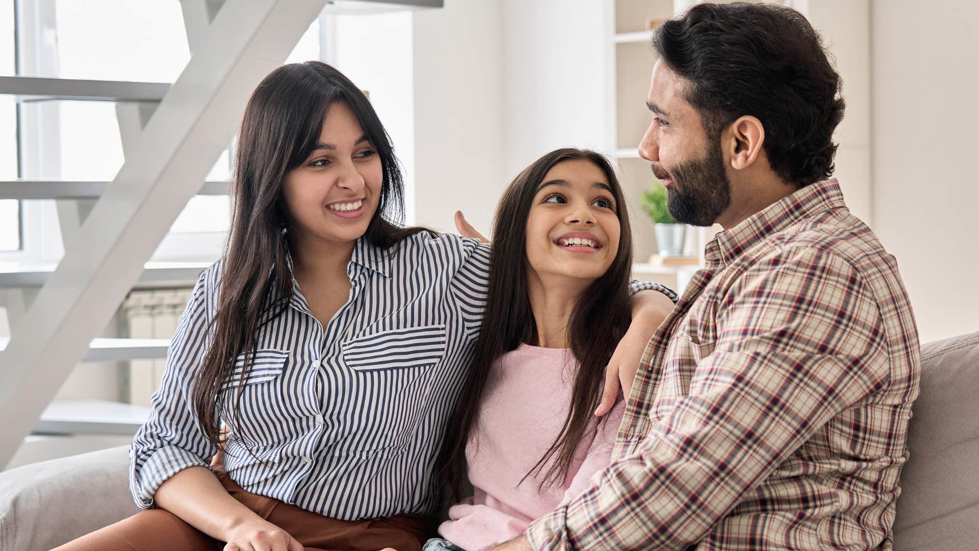 Couple smiling and talking to their teenage daughter.