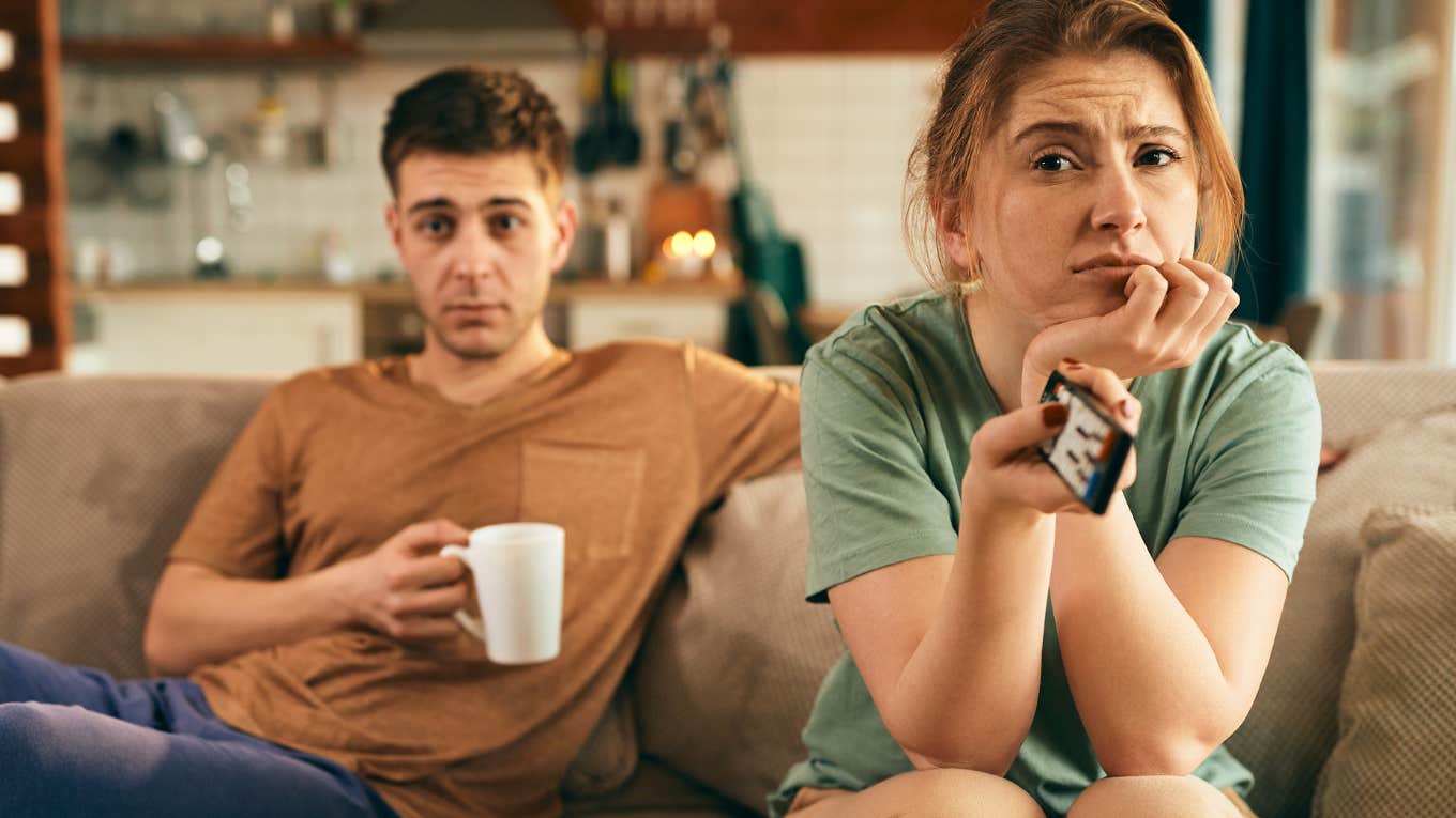 Married couple looking bored and sitting on the couch together. 