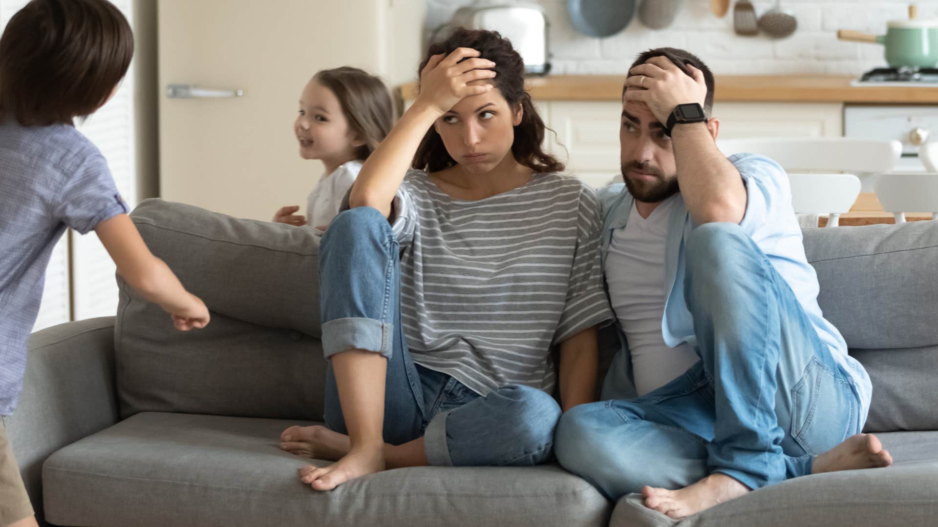 Couple looking stressed while their kids run around them