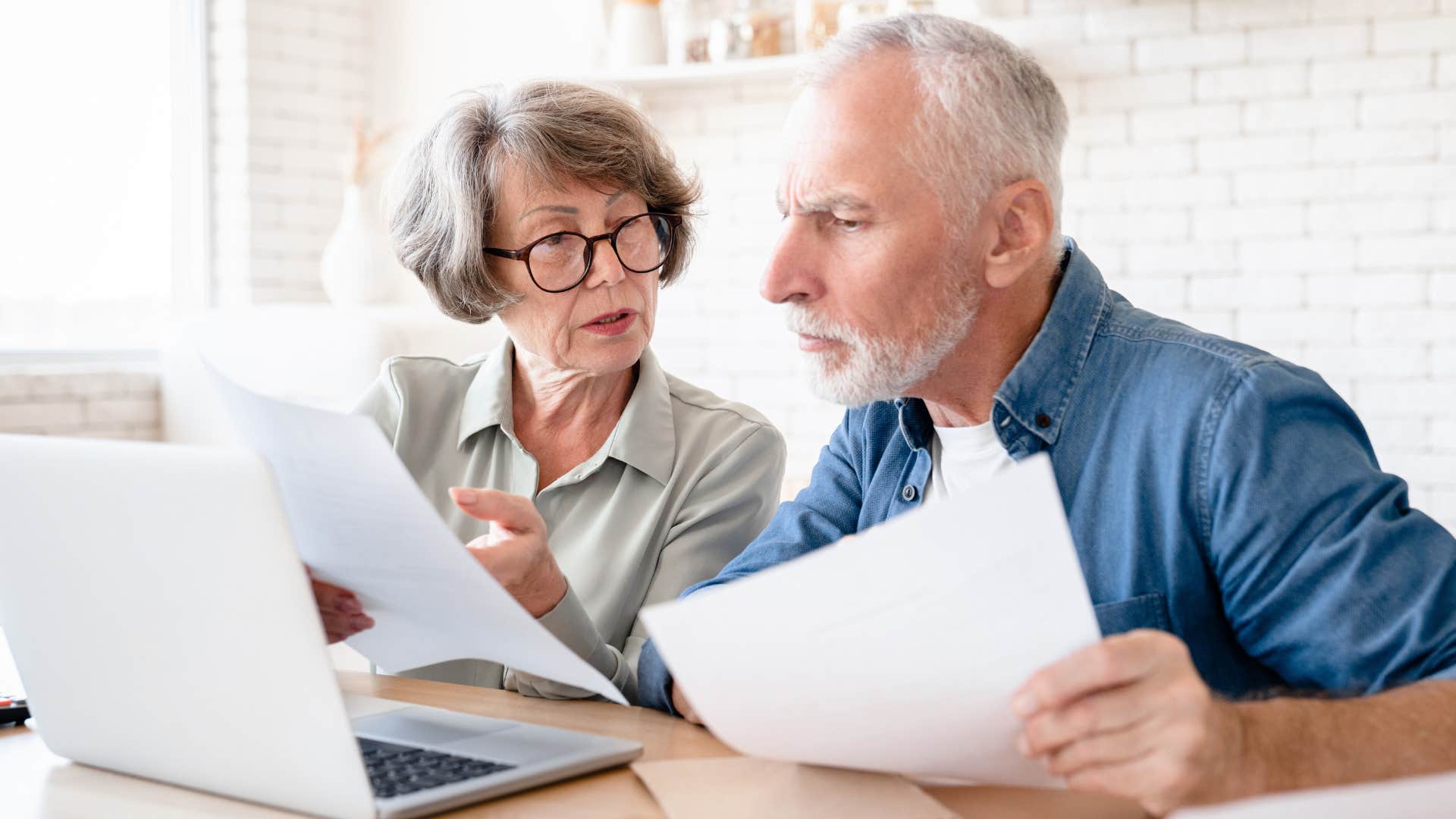 Older couple sitting at a table and looking at papers together