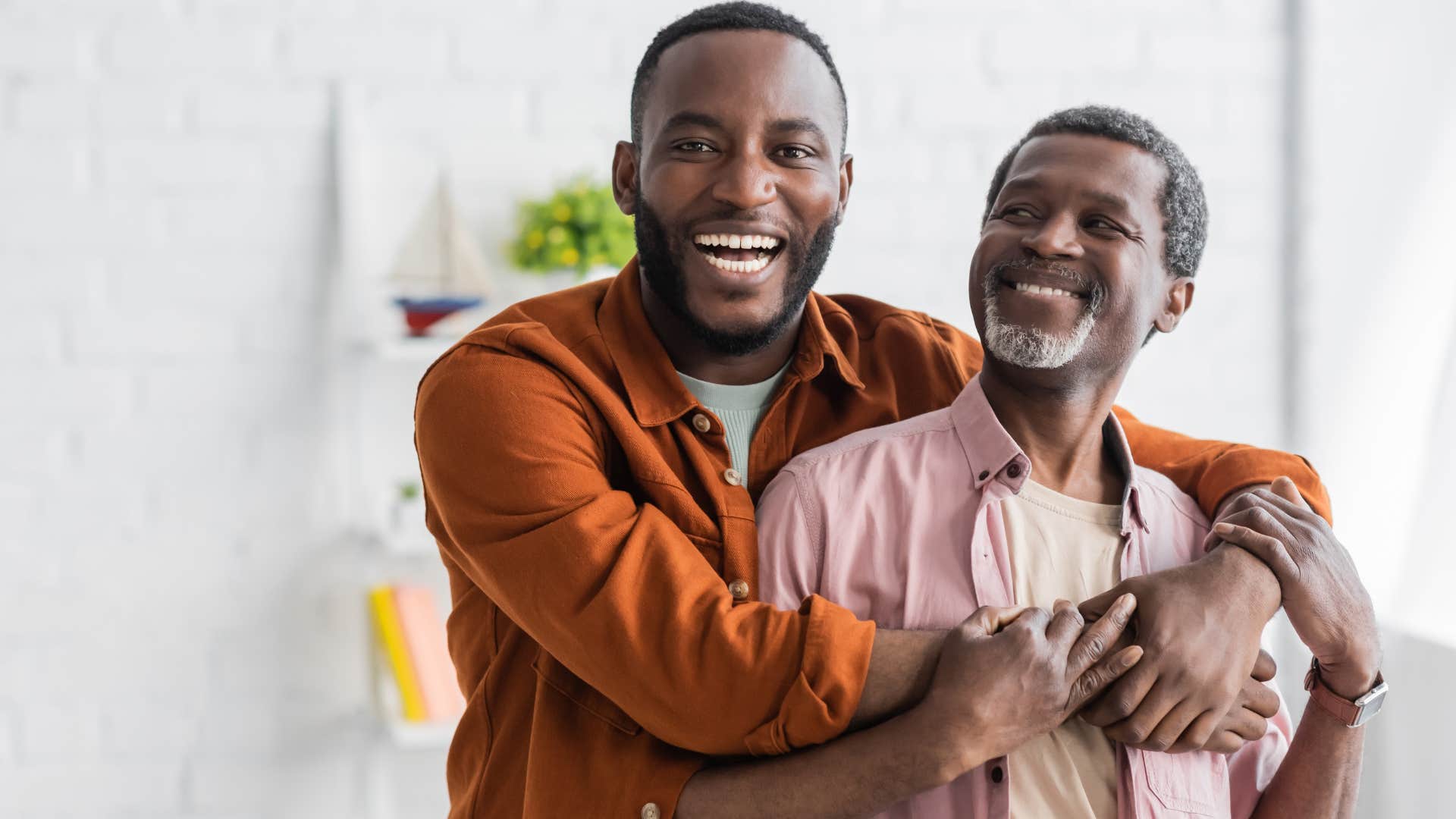 Adult son hugging his dad at home.