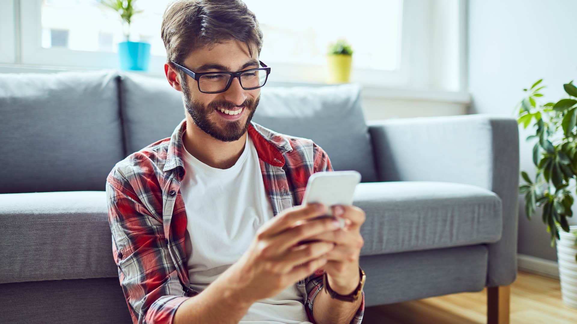 Man smiling and texting on his phone.