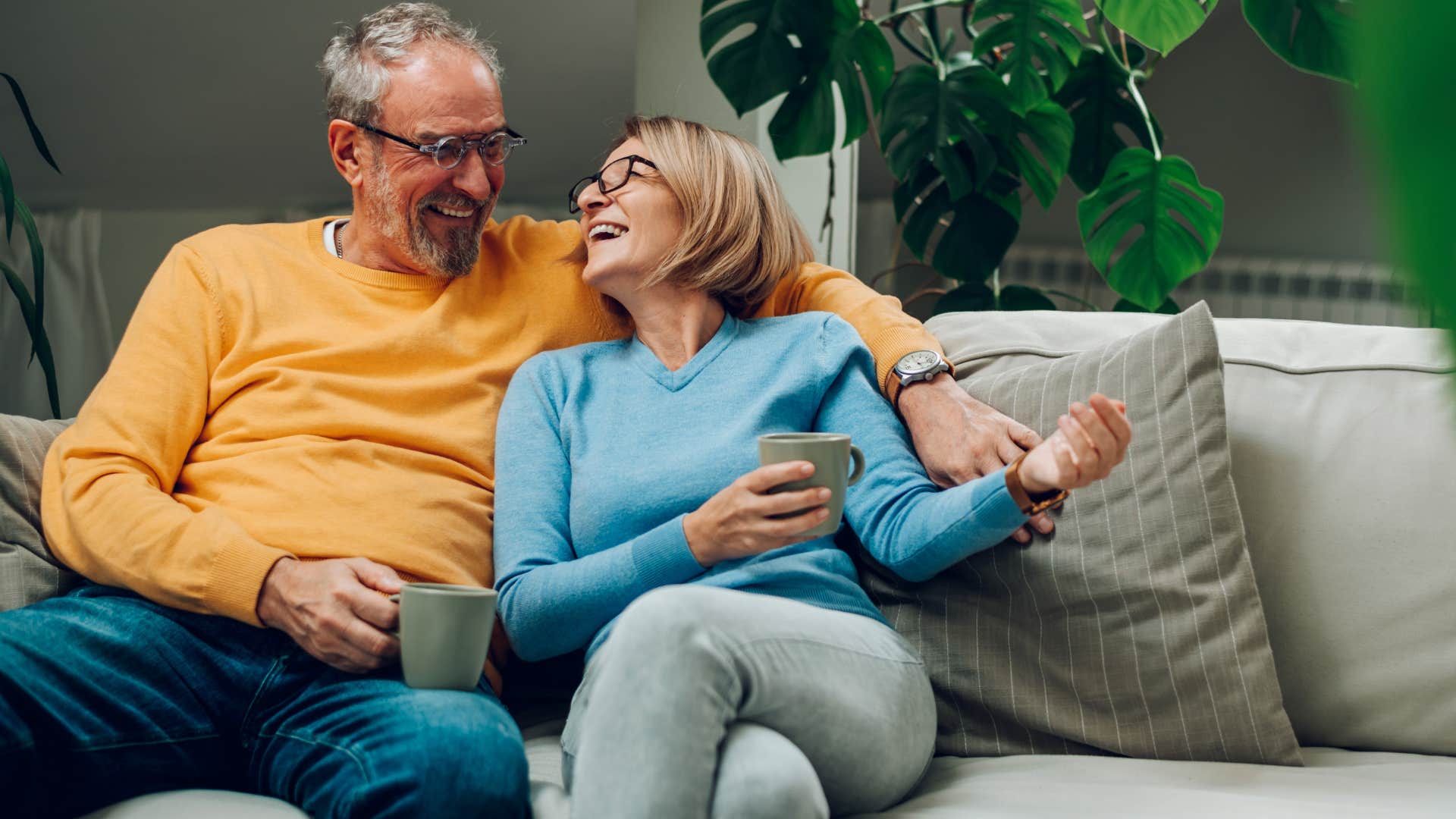 Older couple smiling and sitting on the couch together.