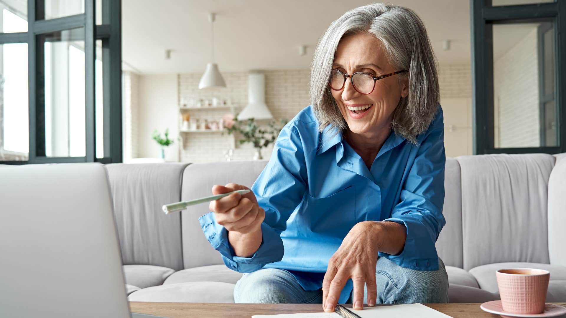 Older woman smiling and talking to someone on her laptop.