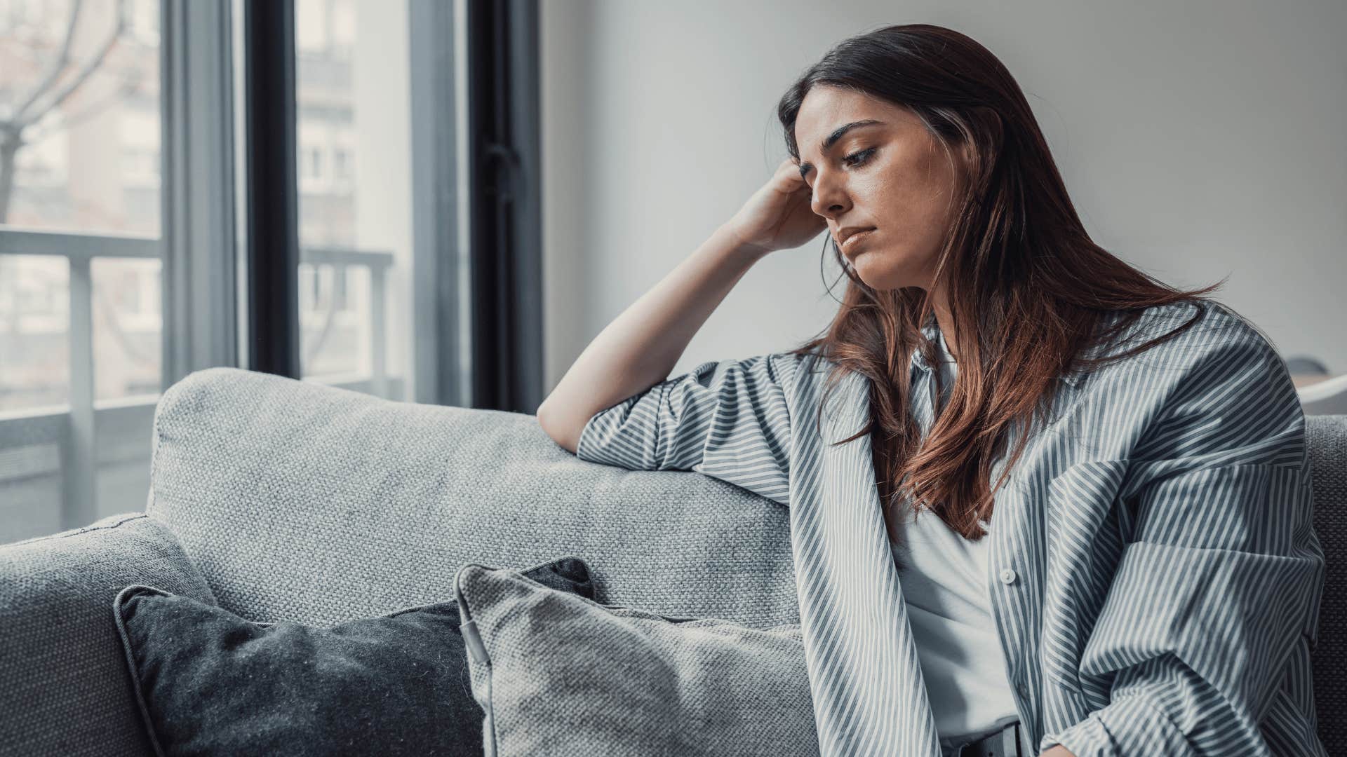 woman looking distraught while sitting on the couch