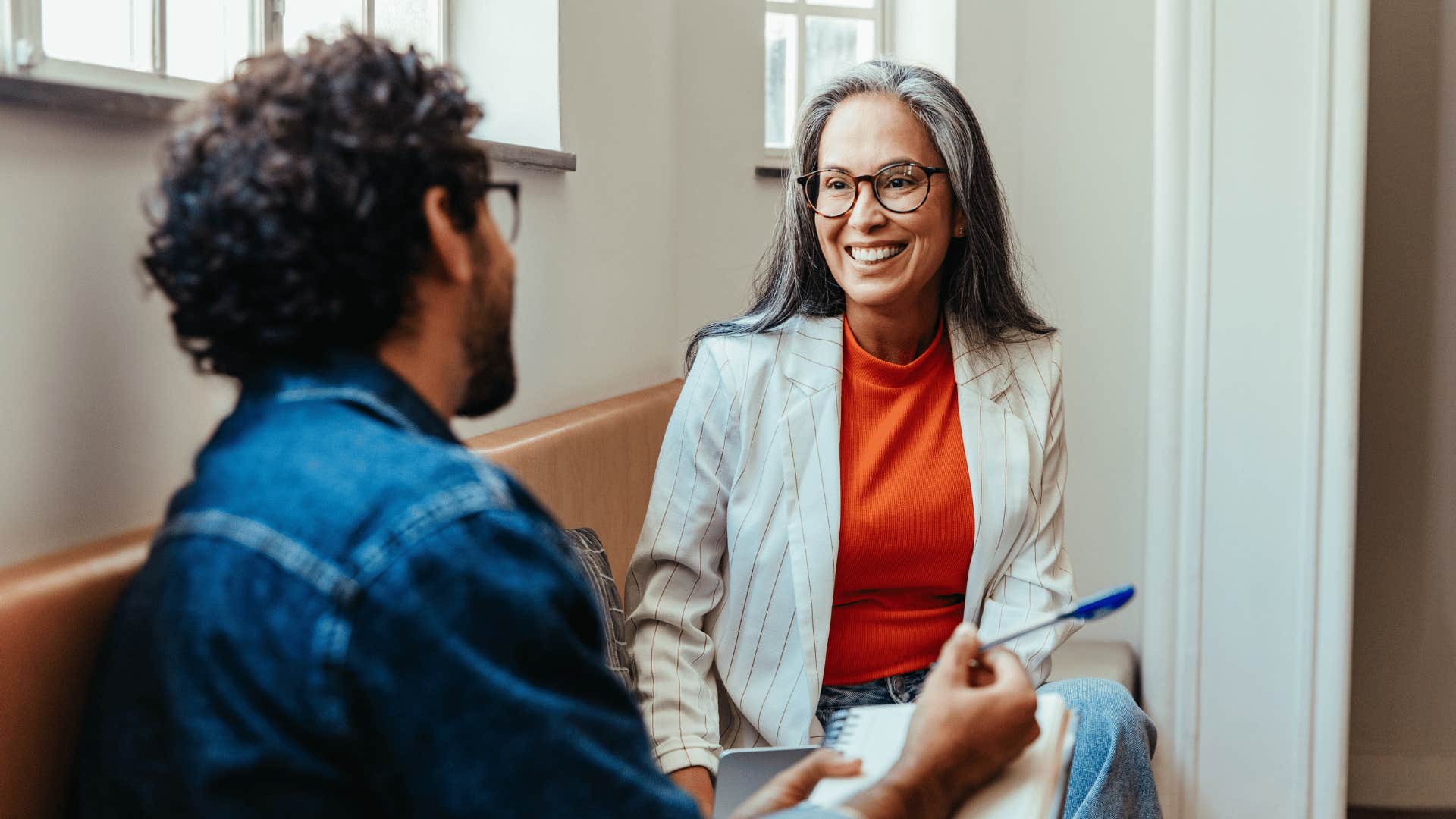 man writing down notes while talking to woman 