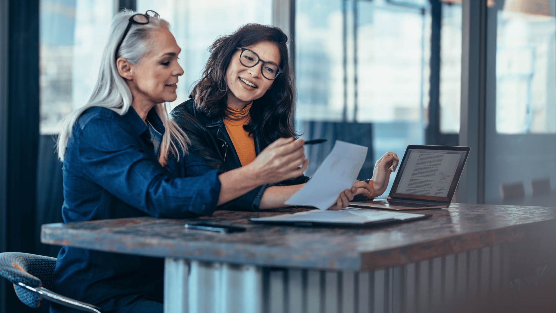 two women looking at document and sitting down next to each other