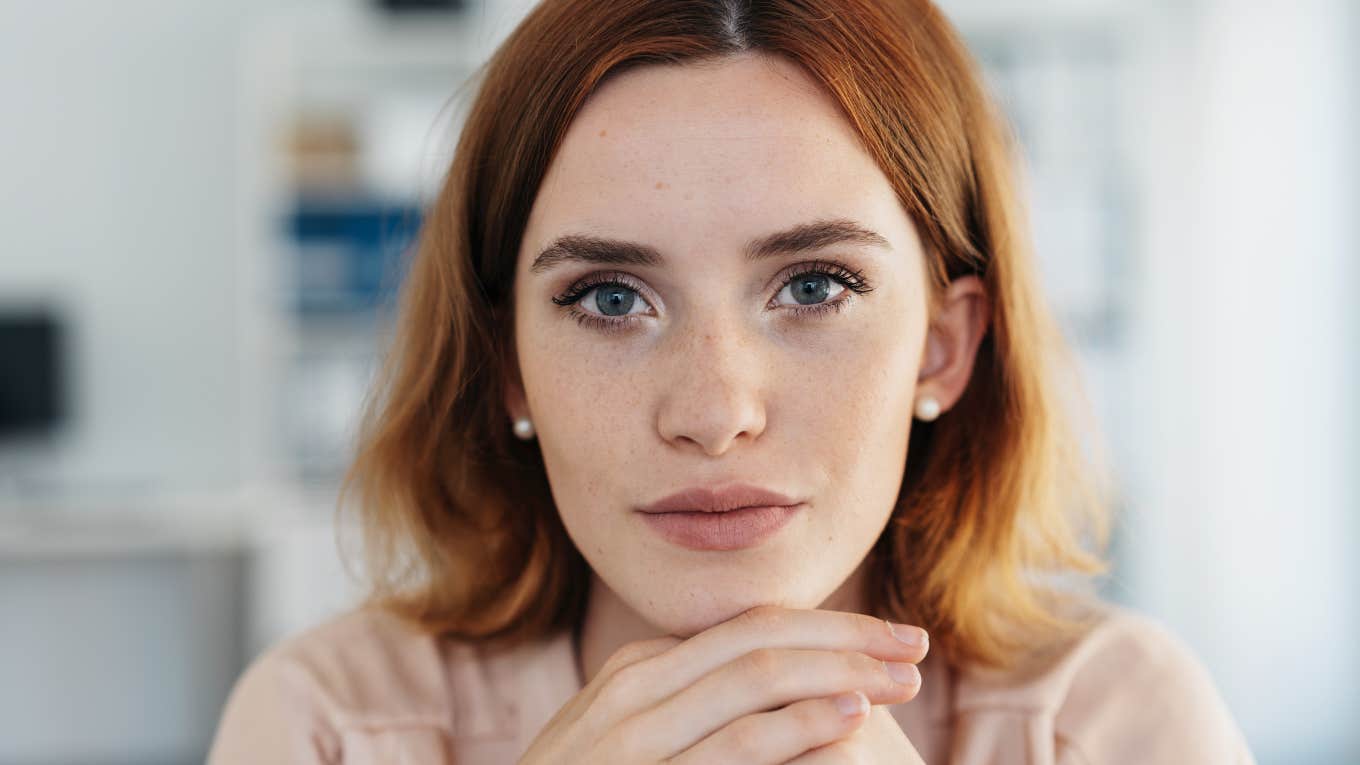 serious redheaded woman with hands on her chin