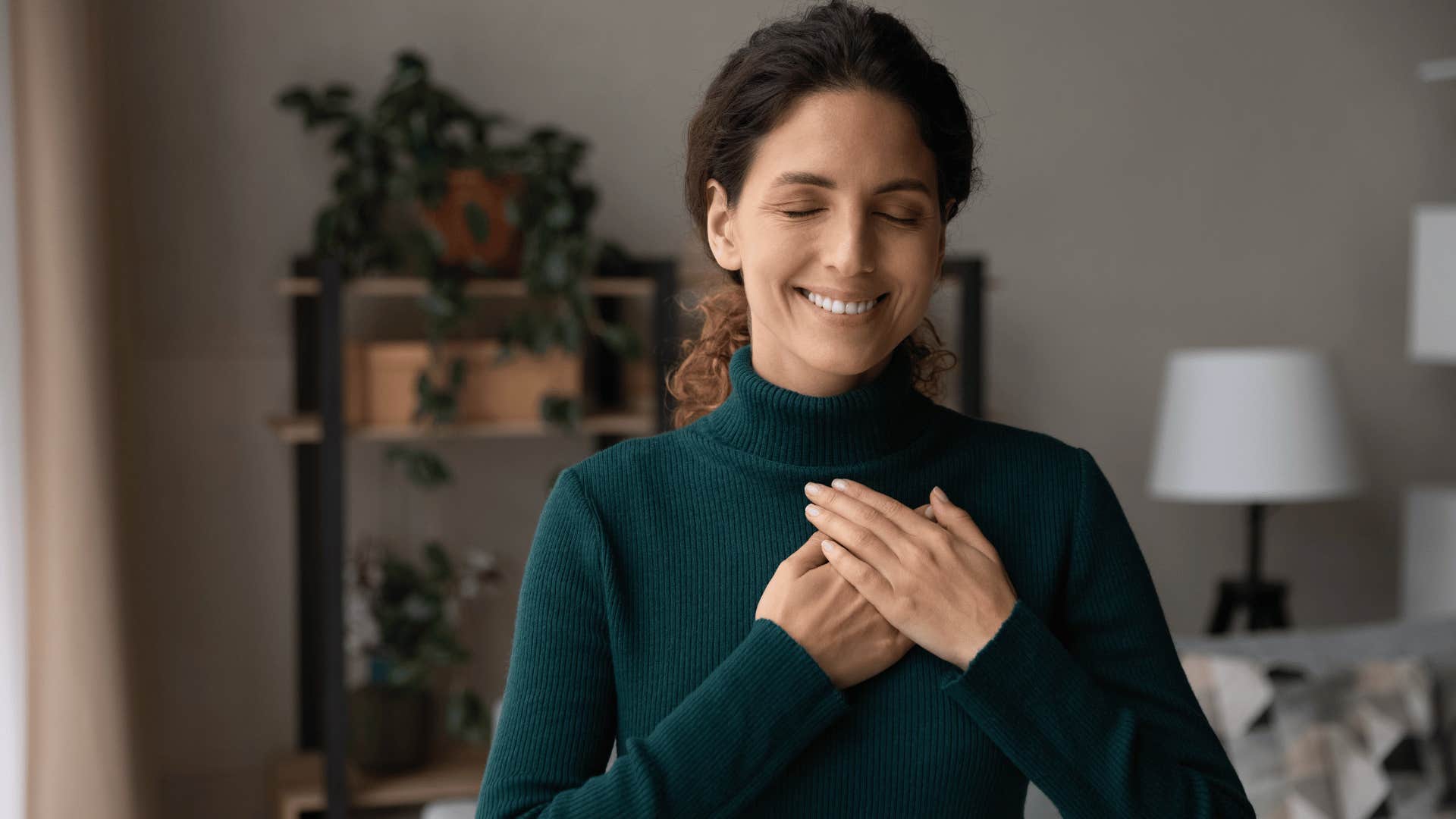 woman smiling and holding hand over heart