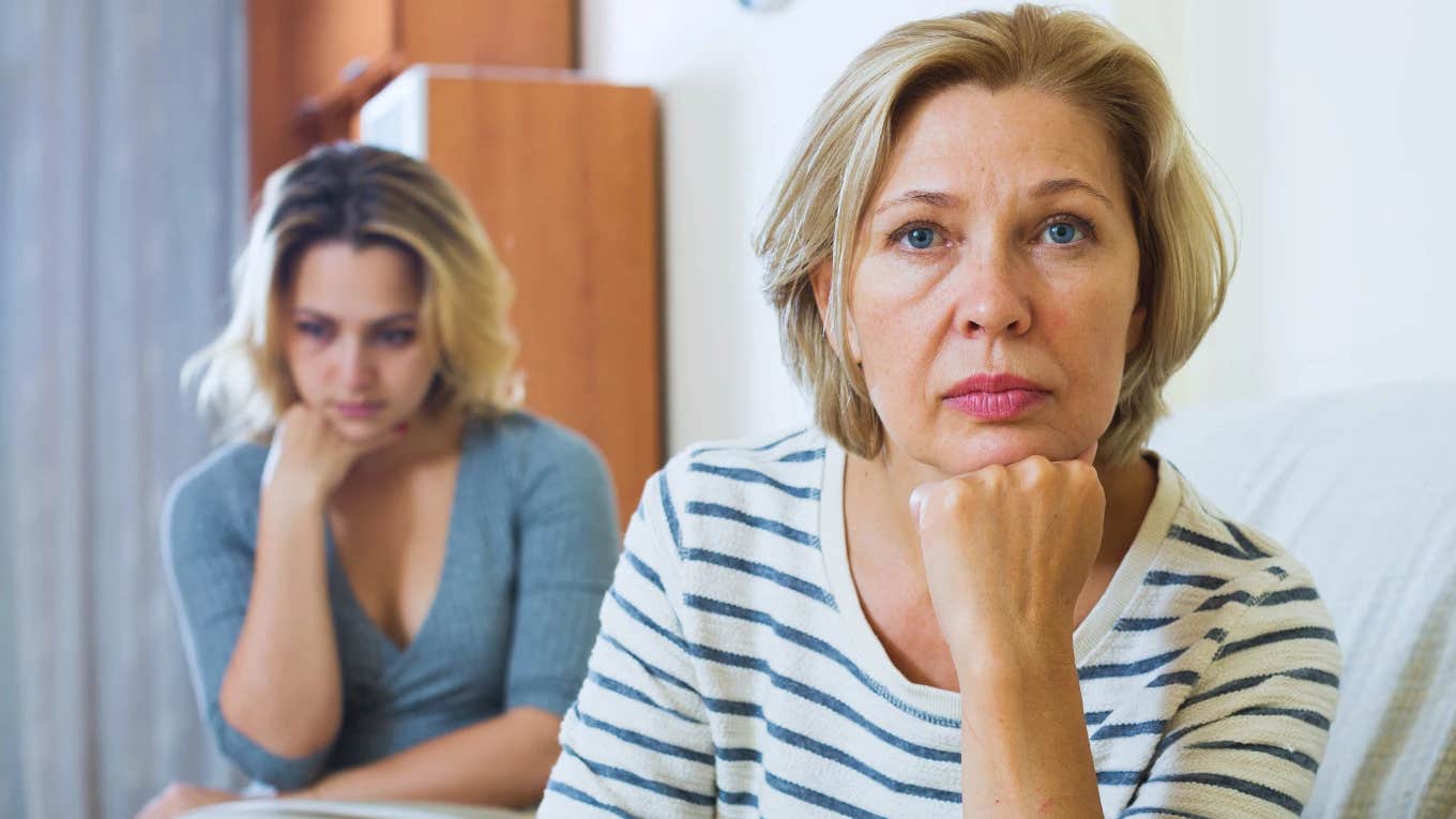 angry mother with sad daughter in background