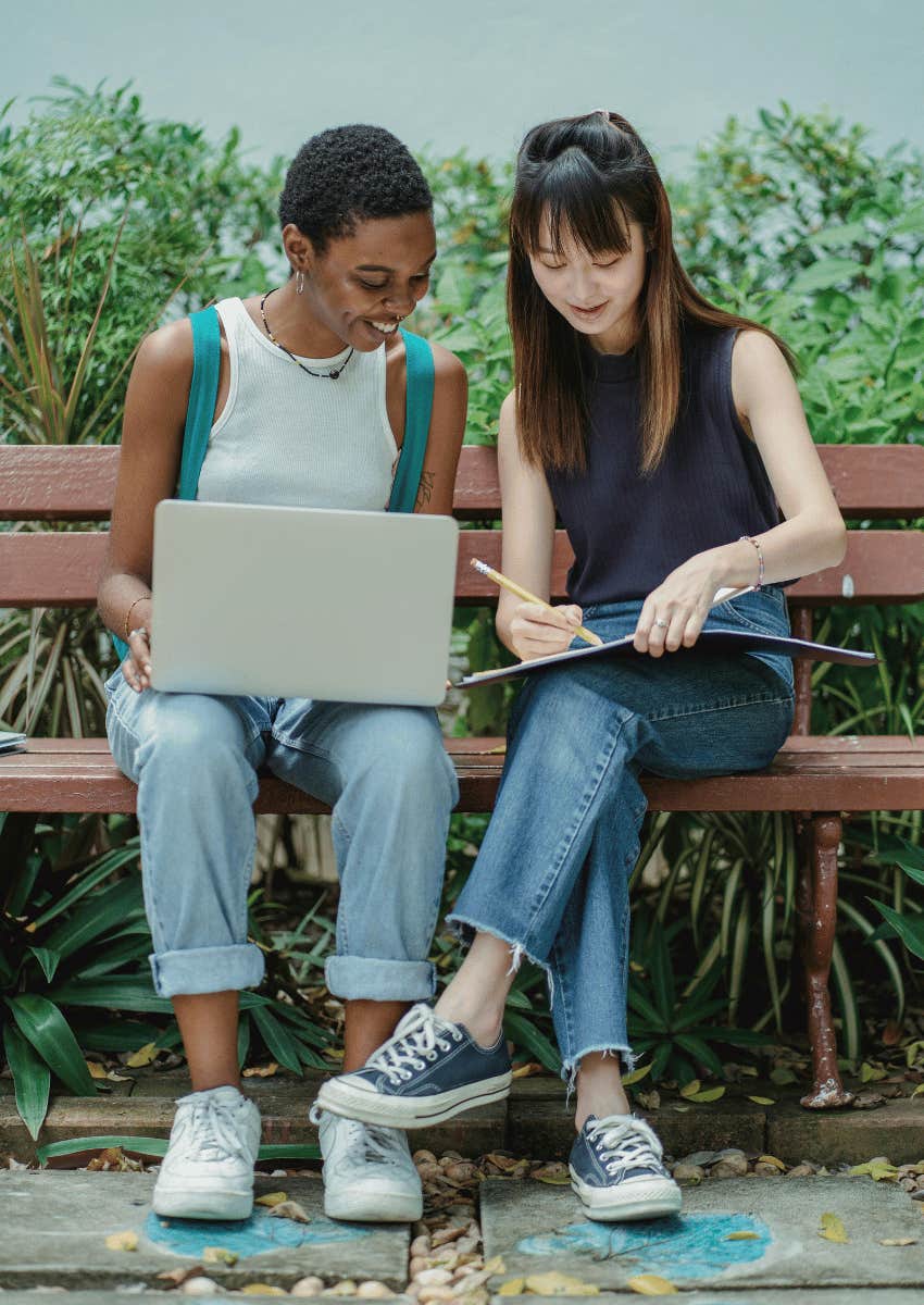 two young woman sitting on a bench together