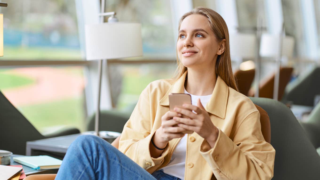 Unemployed Gen Z woman smiling holding phone