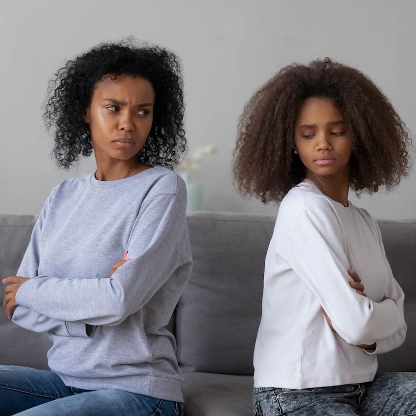 Mother and daughter sit back to back, arms crossed, in anger