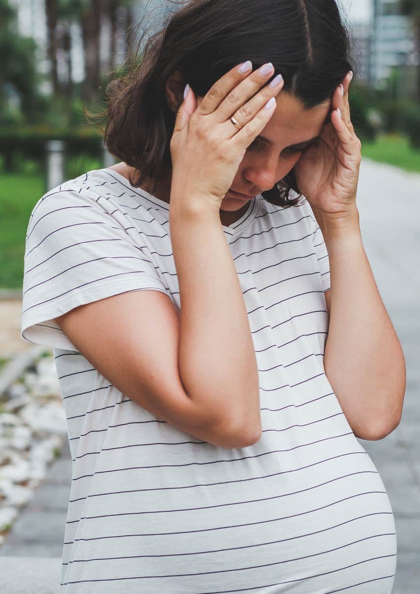 upset pregnant woman looking down with head in hands