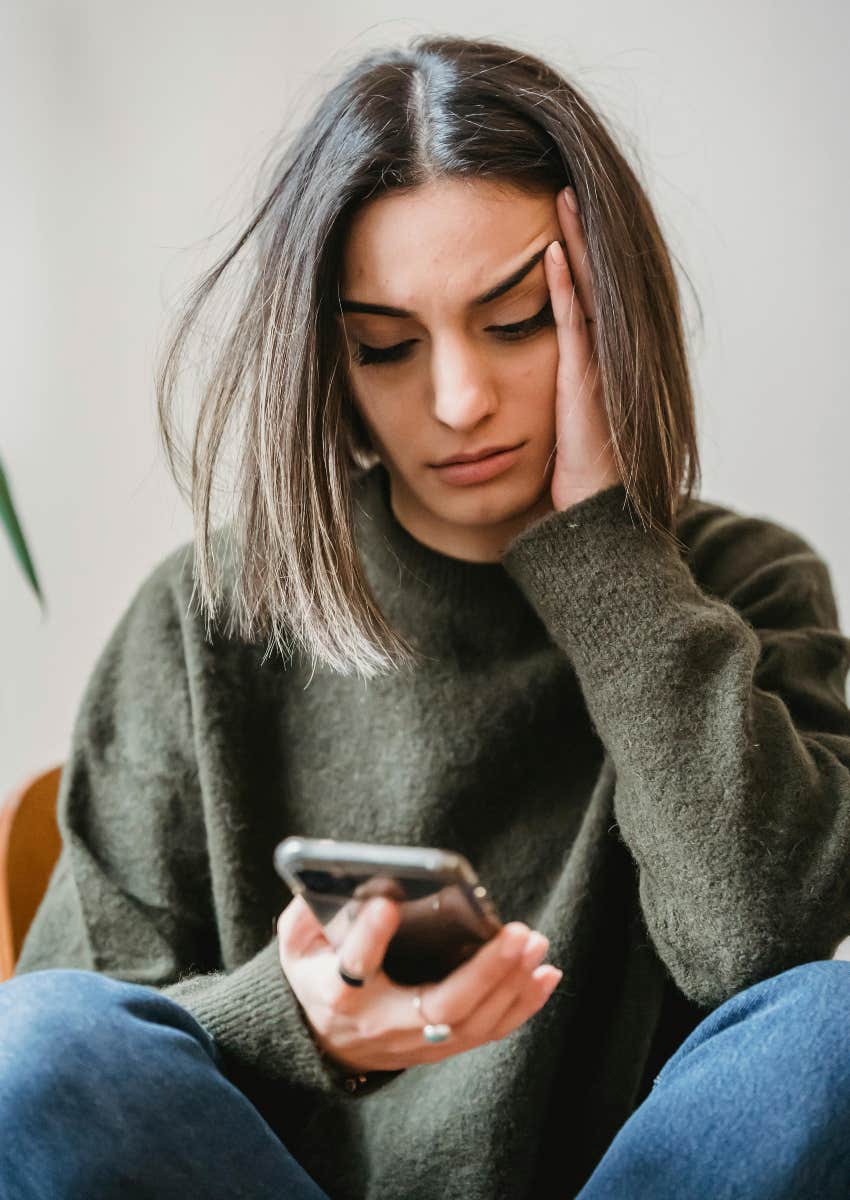 frustrated woman looking down at her phone