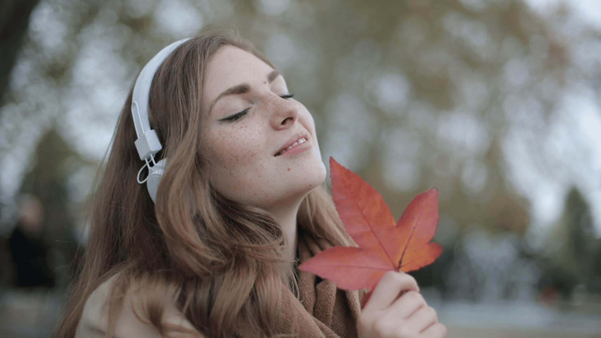 woman listening to music and holding a leaf