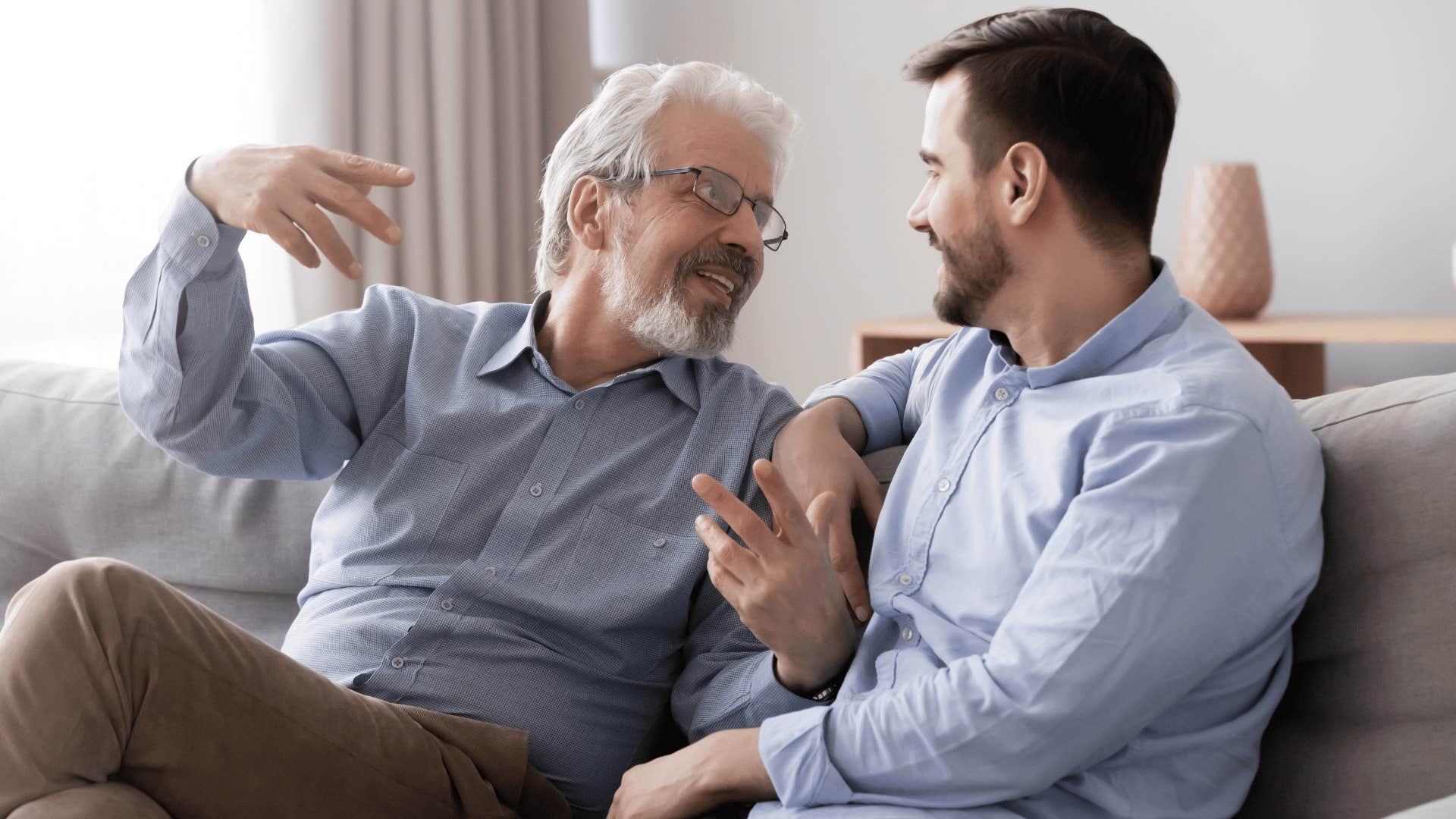 two men talking on the couch while older man explains something 