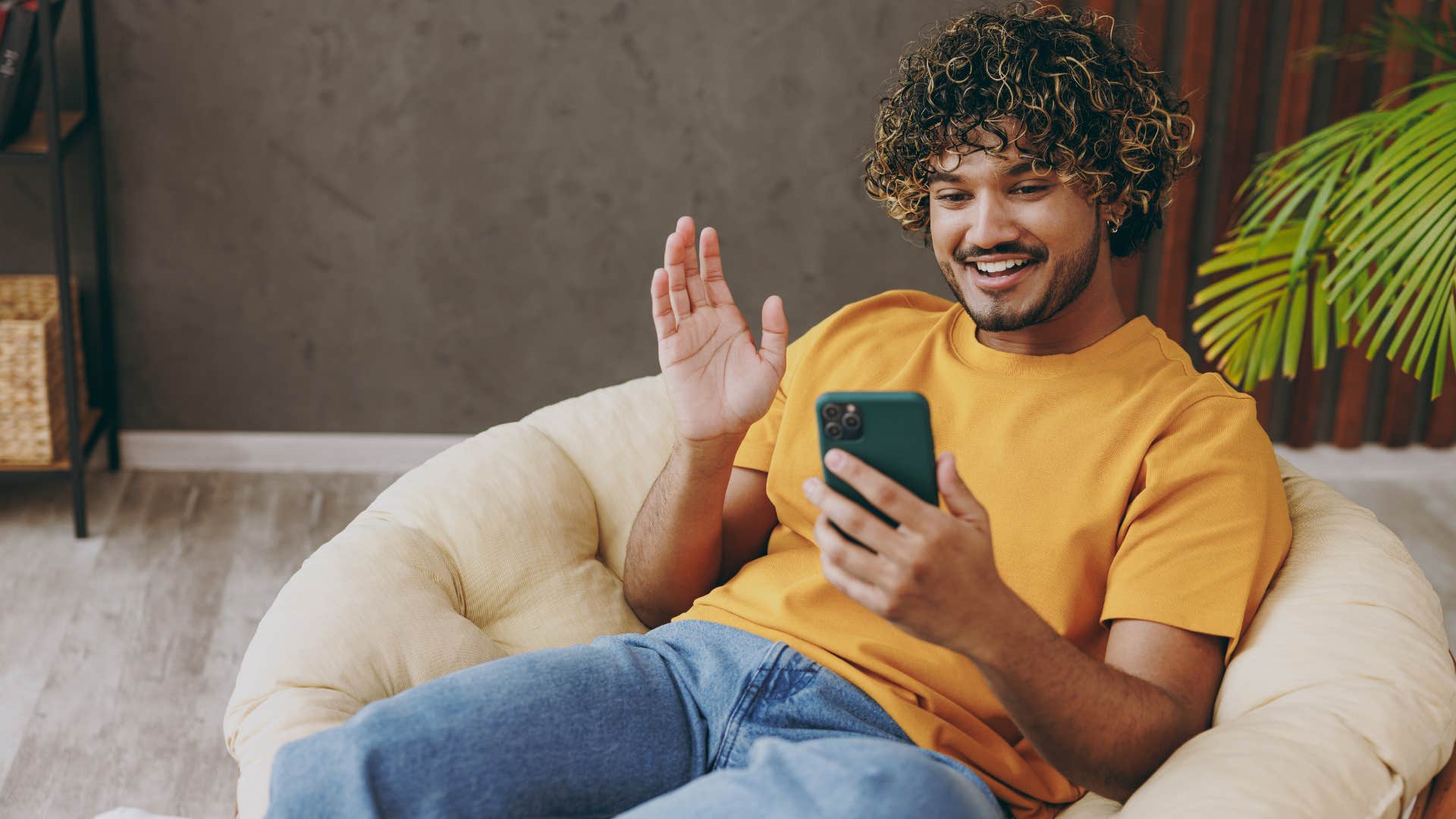 Man smiling and looking at his phone at home.