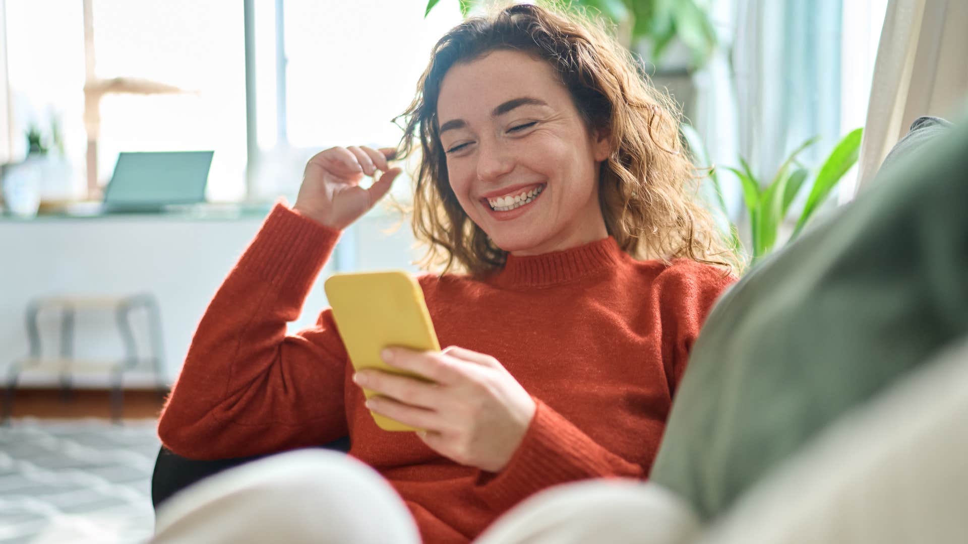 Woman smiling and scrolling on her phone.