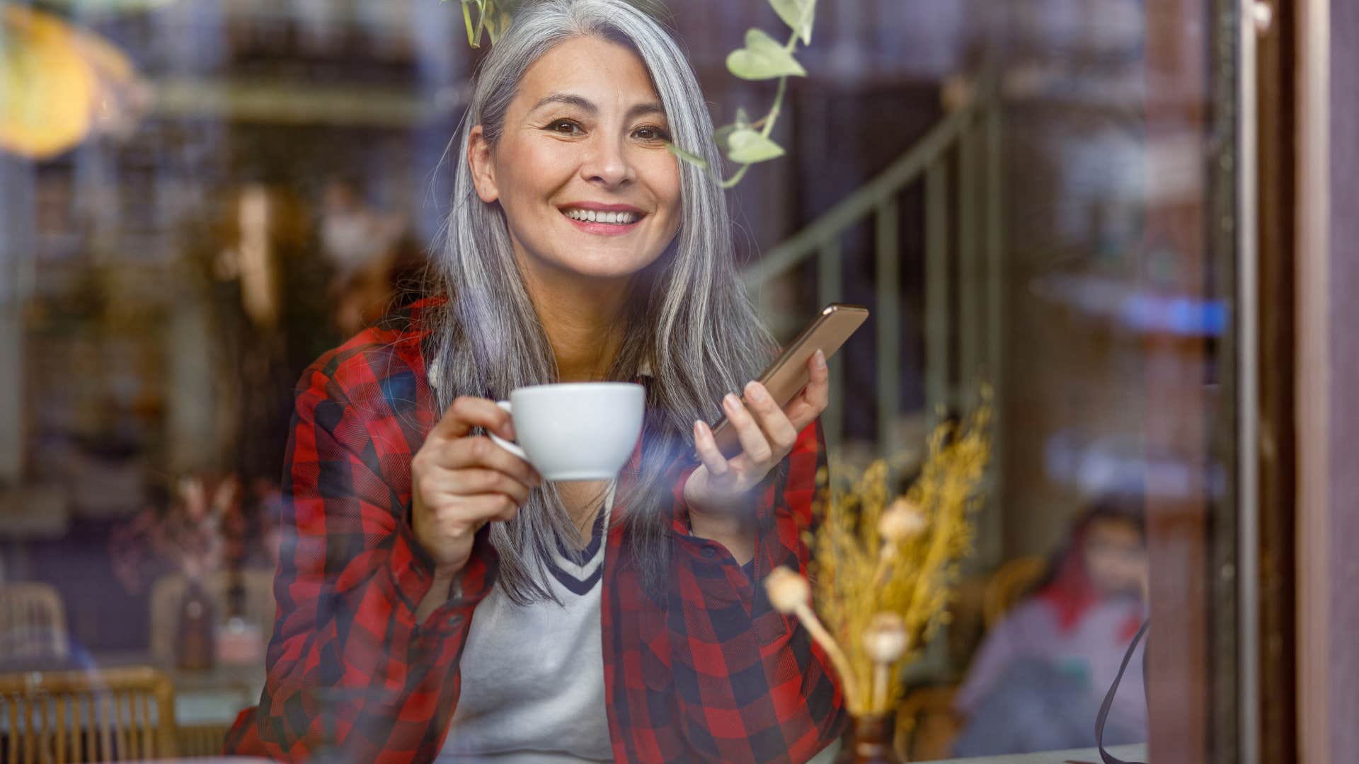 Older woman sitting in a coffee shop drinking coffee.