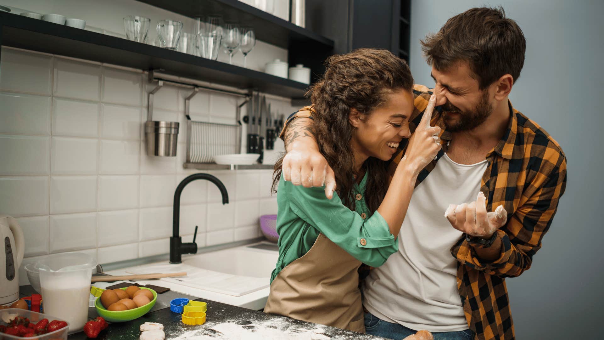 Fun woman plays with happy man in kitchen