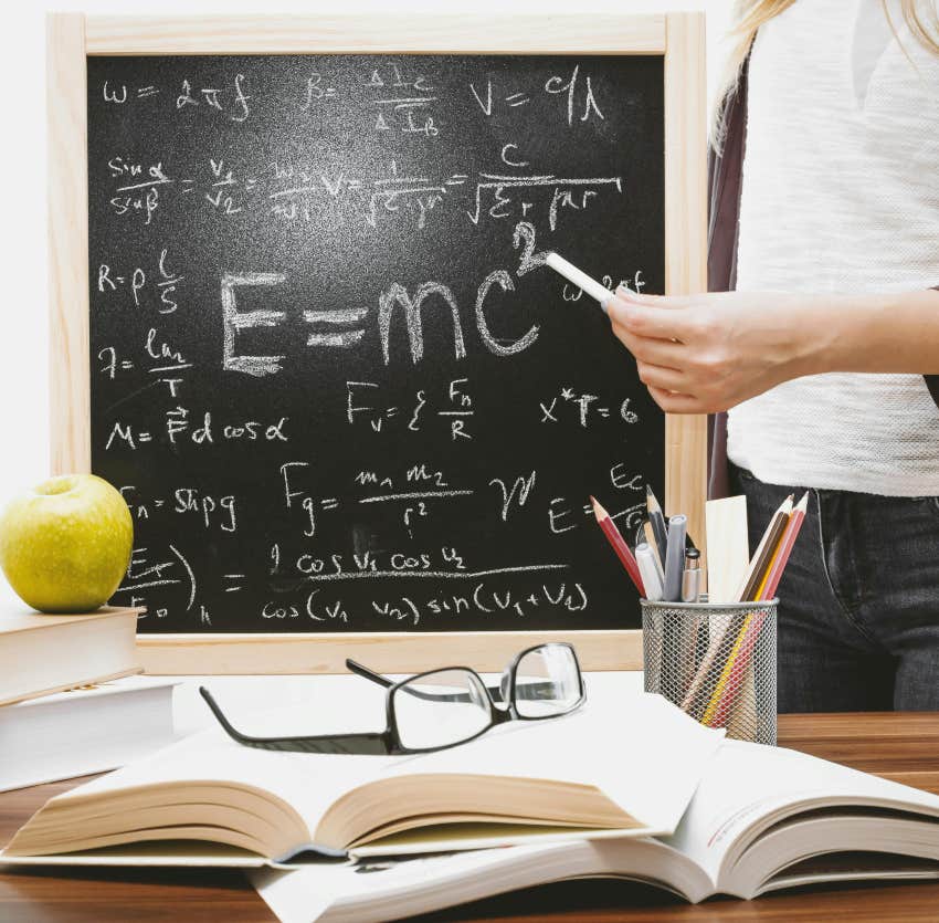 woman standing next to blackboard with quantum physics equations written on it