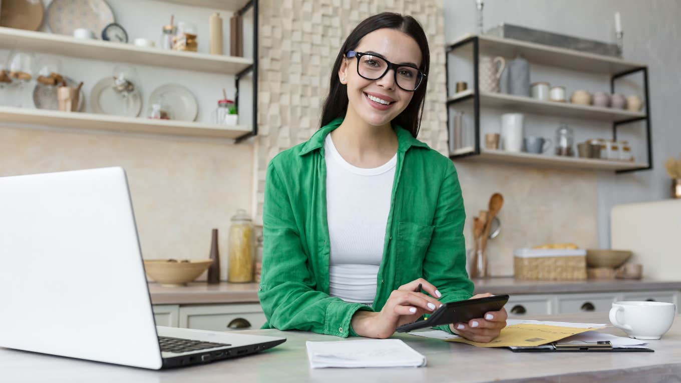 Happy woman separating her money into different bank accounts