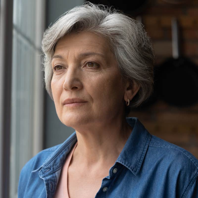 older woman looking out window at home