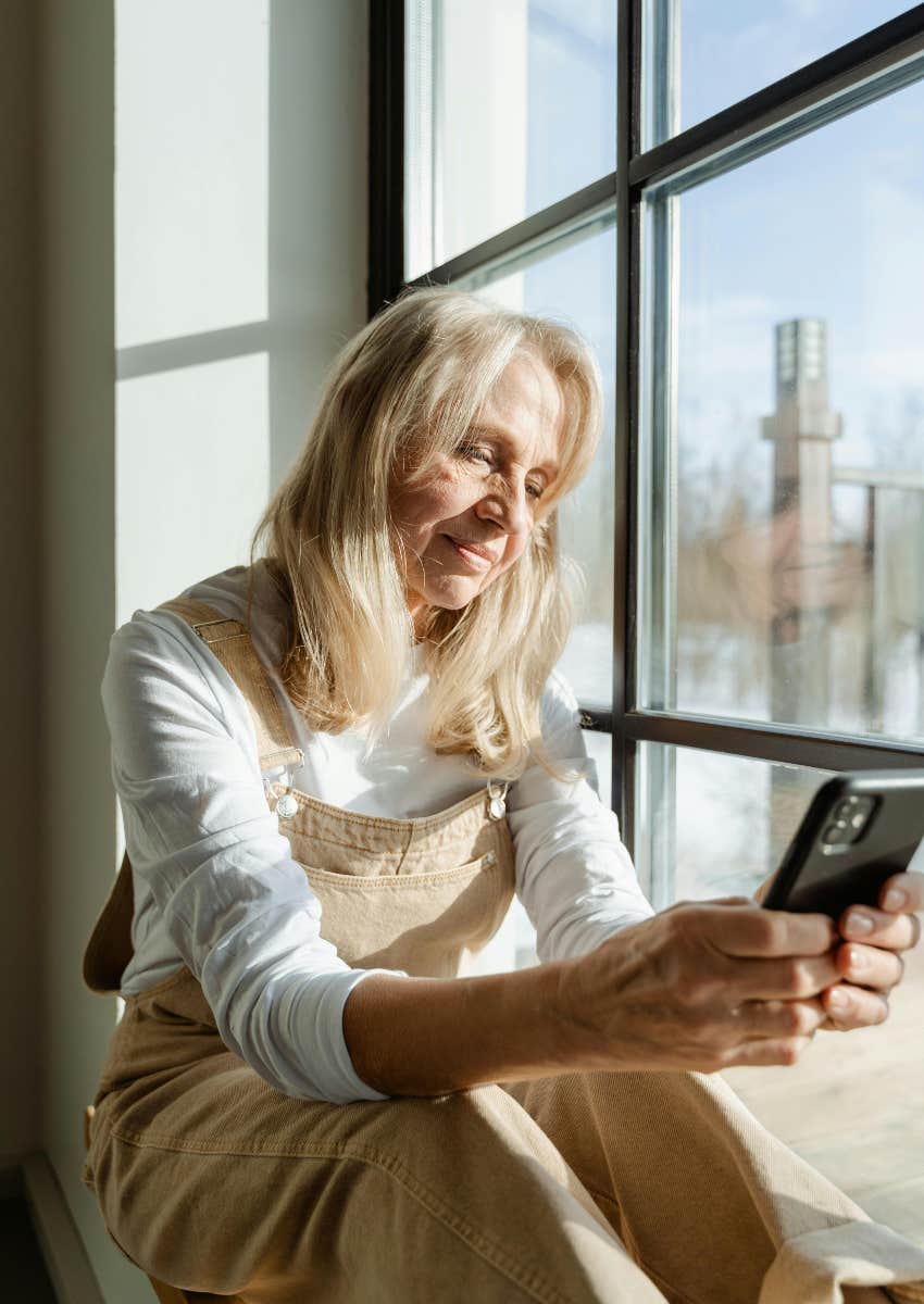 woman in overalls holding black phone