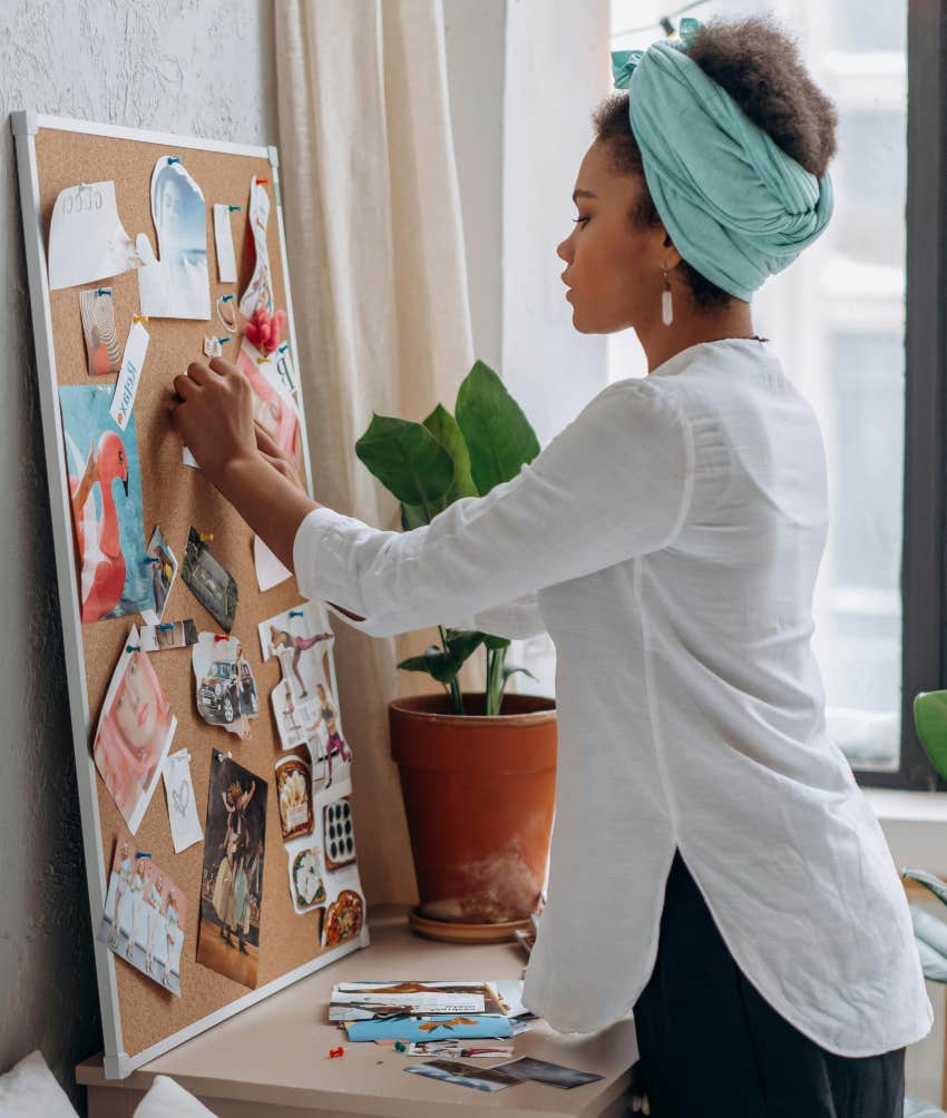 woman putting pictures on bulletin board for vision board