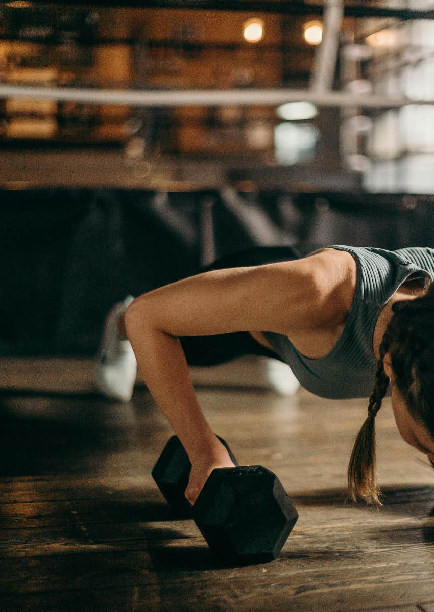 woman doing plank with dumbbell