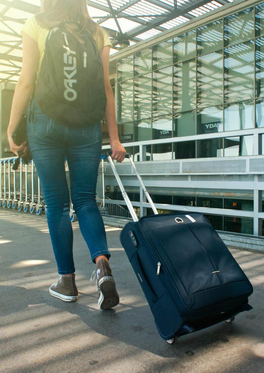 woman pulling her suitcase outside of an airport