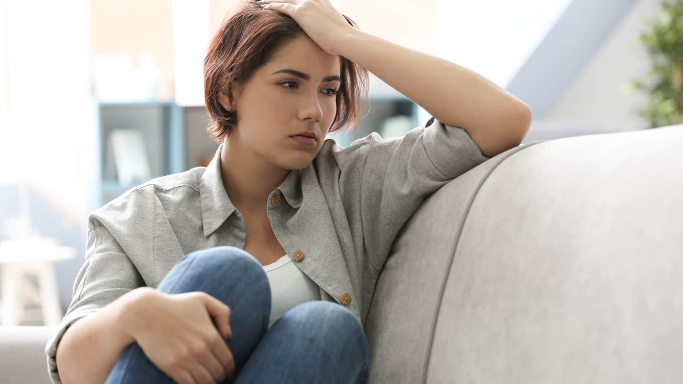 Depressed young woman sitting on sofa at home