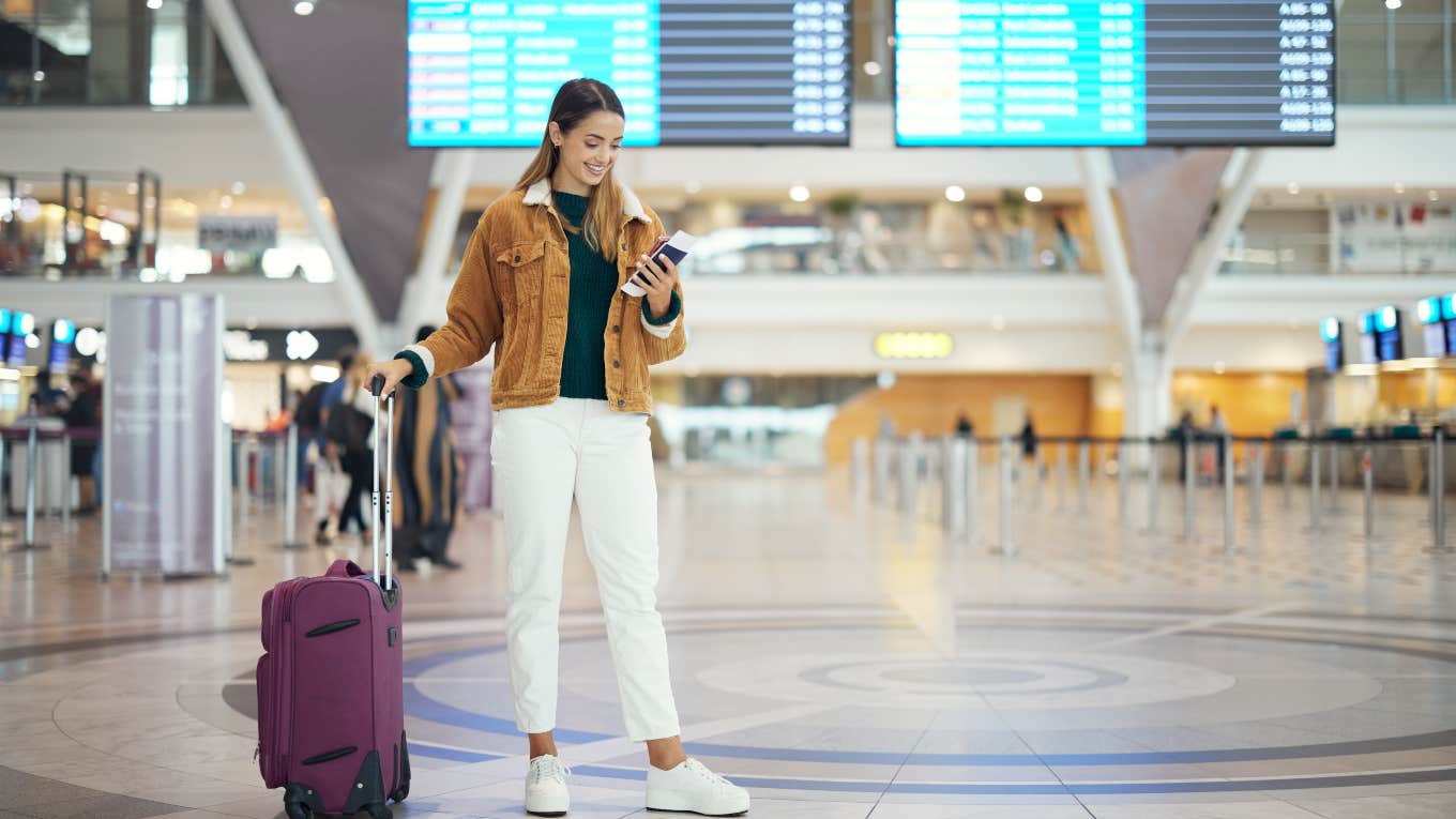 woman standing in the middle of the airport with her suitcase