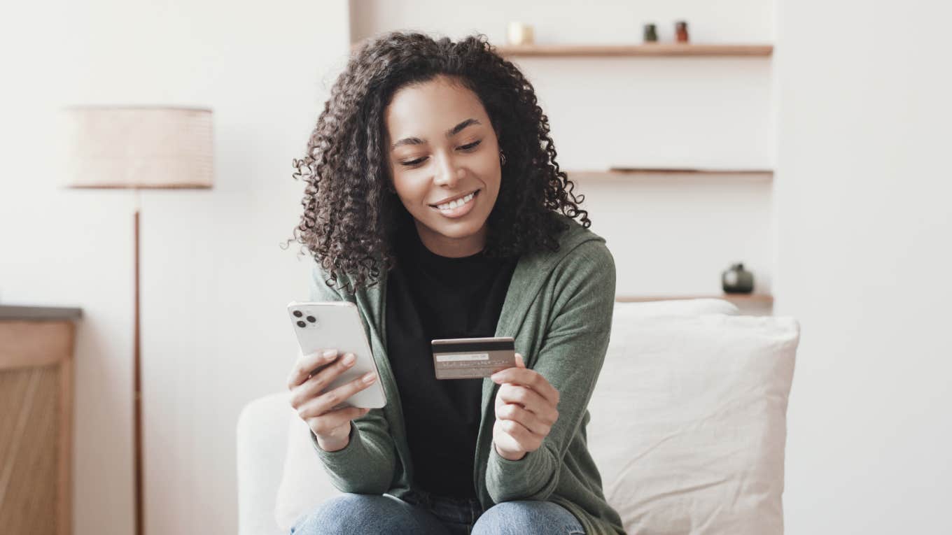 young smiling woman holding phone and credit card