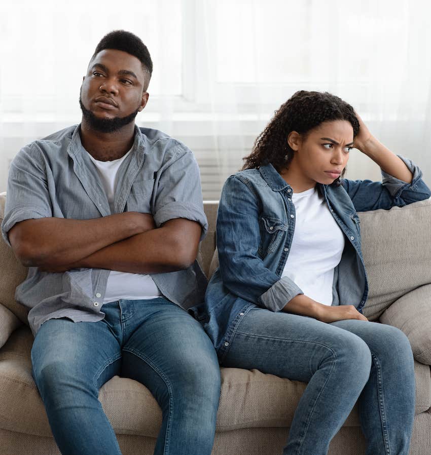 Detached woman sits on couch with defensive man