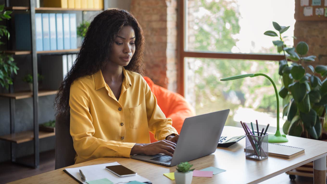 focused woman typing on laptop in office