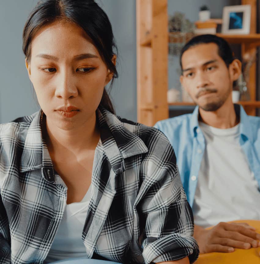 Gaslighting man sits behind worried woman