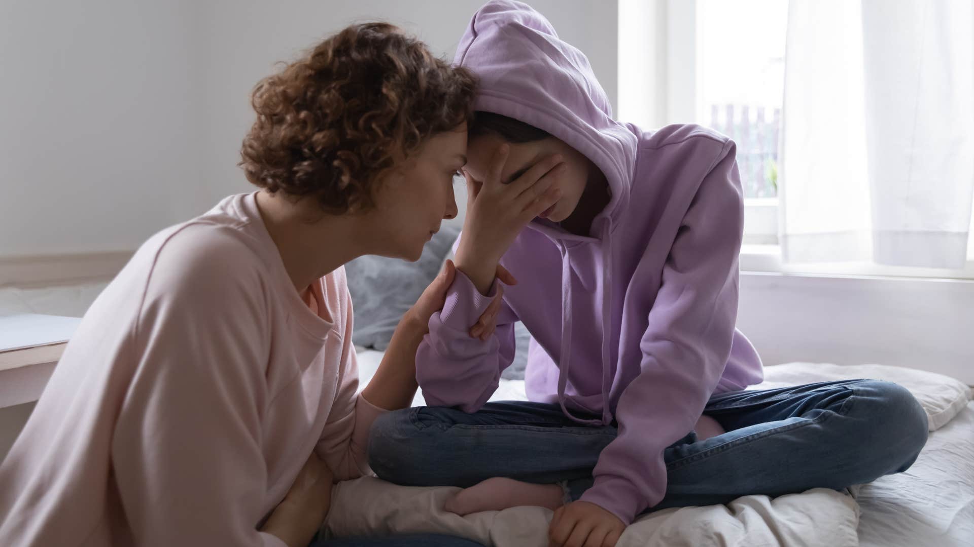 Woman comforting her upset teenage daughter.