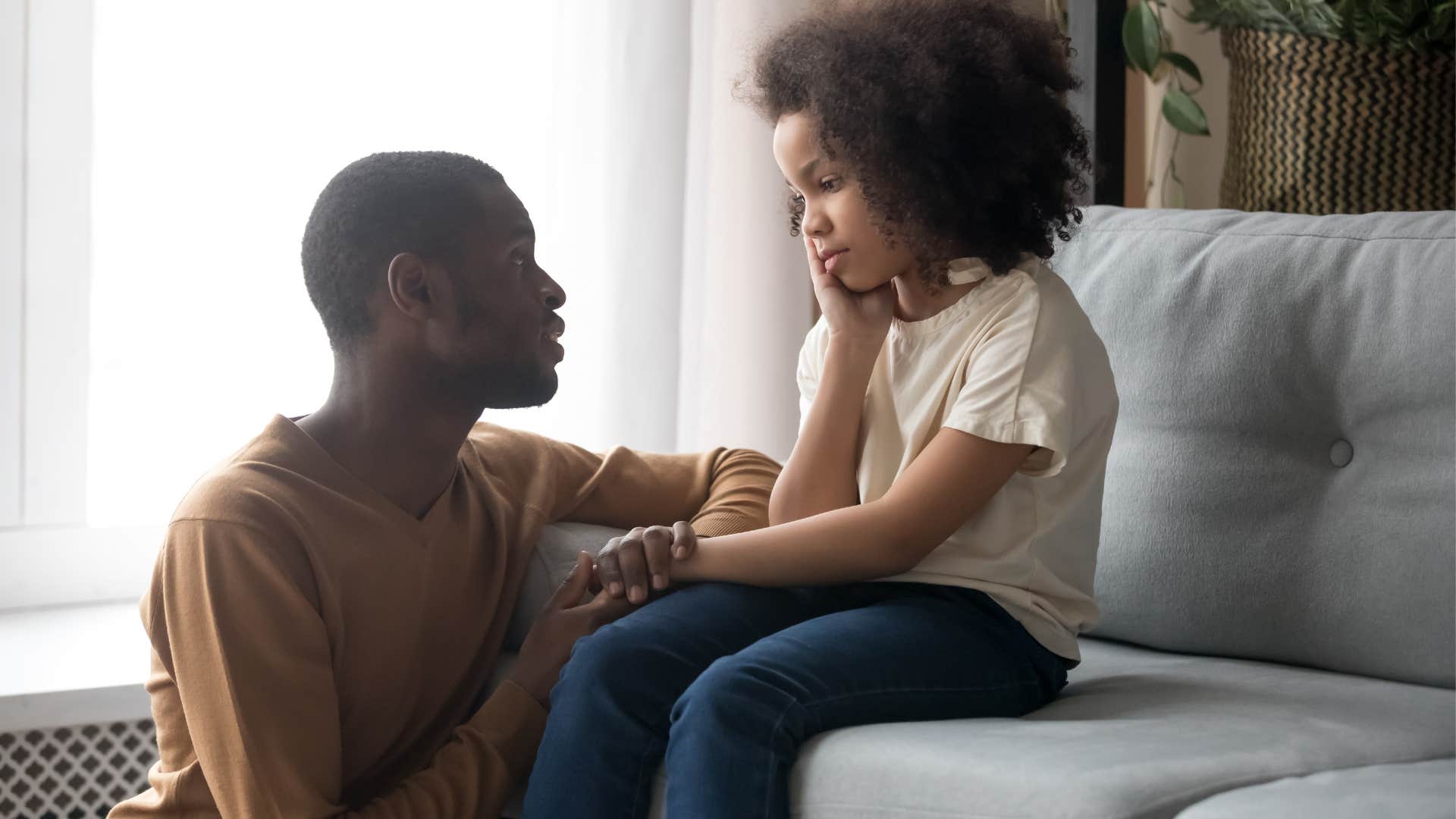 Man kneeling down and talking to his young daughter.